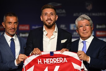 Atletico Madrid's new Mexican midfielder Hector Herrera holds his new jersey next to the Spanish football club's president Enrique Cerezo (R) and sports director Andrea Berta (L) during his official presentation at the Wanda Metropolitan stadium in Madrid