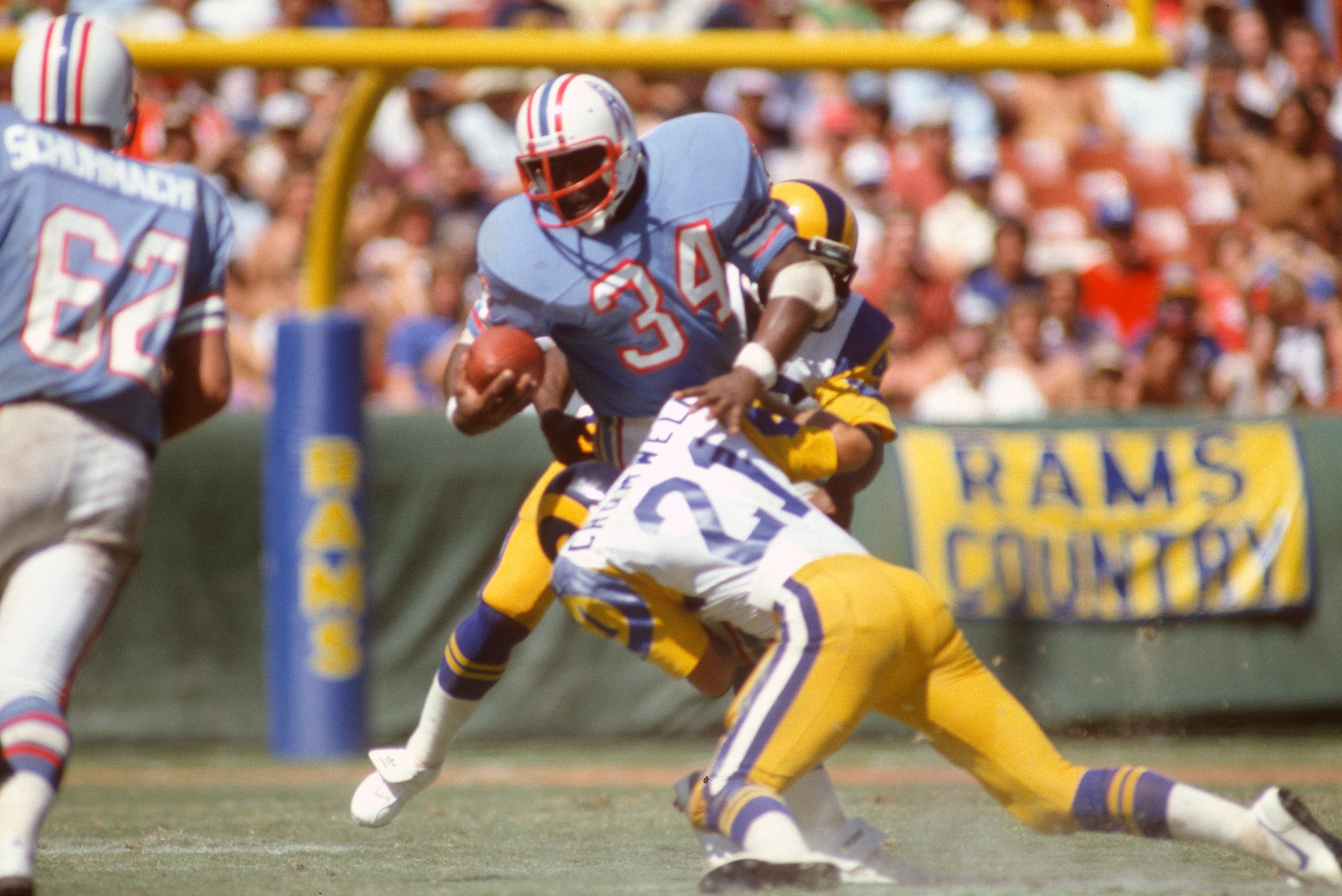 ANAHEIM, CA - SEPTEMBER 6:  Earl Campbell #34 of the Houston Oilers gets tackled by Nolan Cromwell #21 of the Los Angeles Rams during an NFL Football game September 6, 1981 at Anaheim Stadium in Anaheim, California. Campbell  played for the Oilers from 19