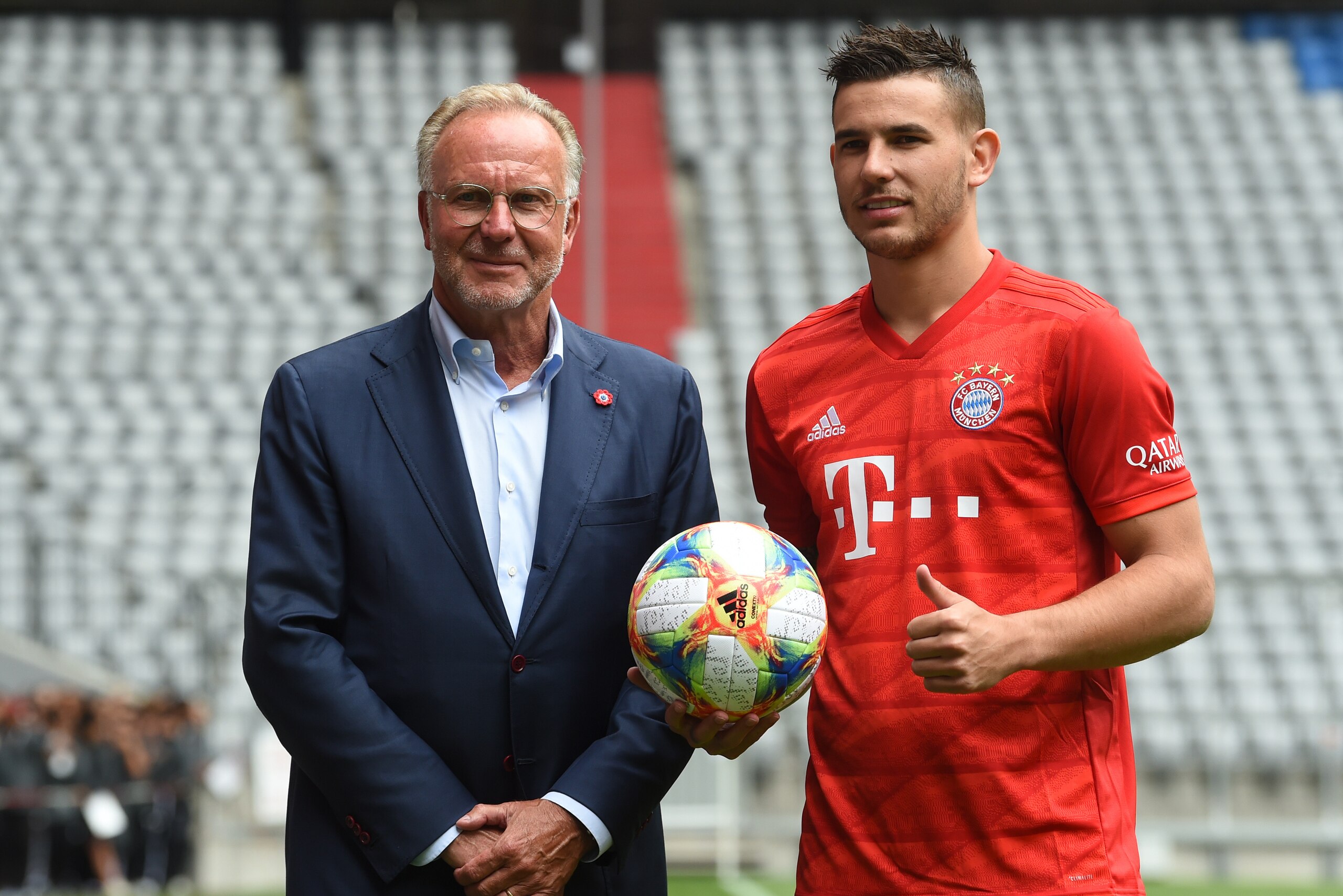 New Bayern Munich French defender Lucas Hernandez (R) and Bayern Munich's CEO Karl-Heinz Rummenigge (L) pose during a presentation in the stadium in Munich, southern Germany, on July 8, 2019. (Photo by Christof STACHE / AFP)        (Photo credit should re
