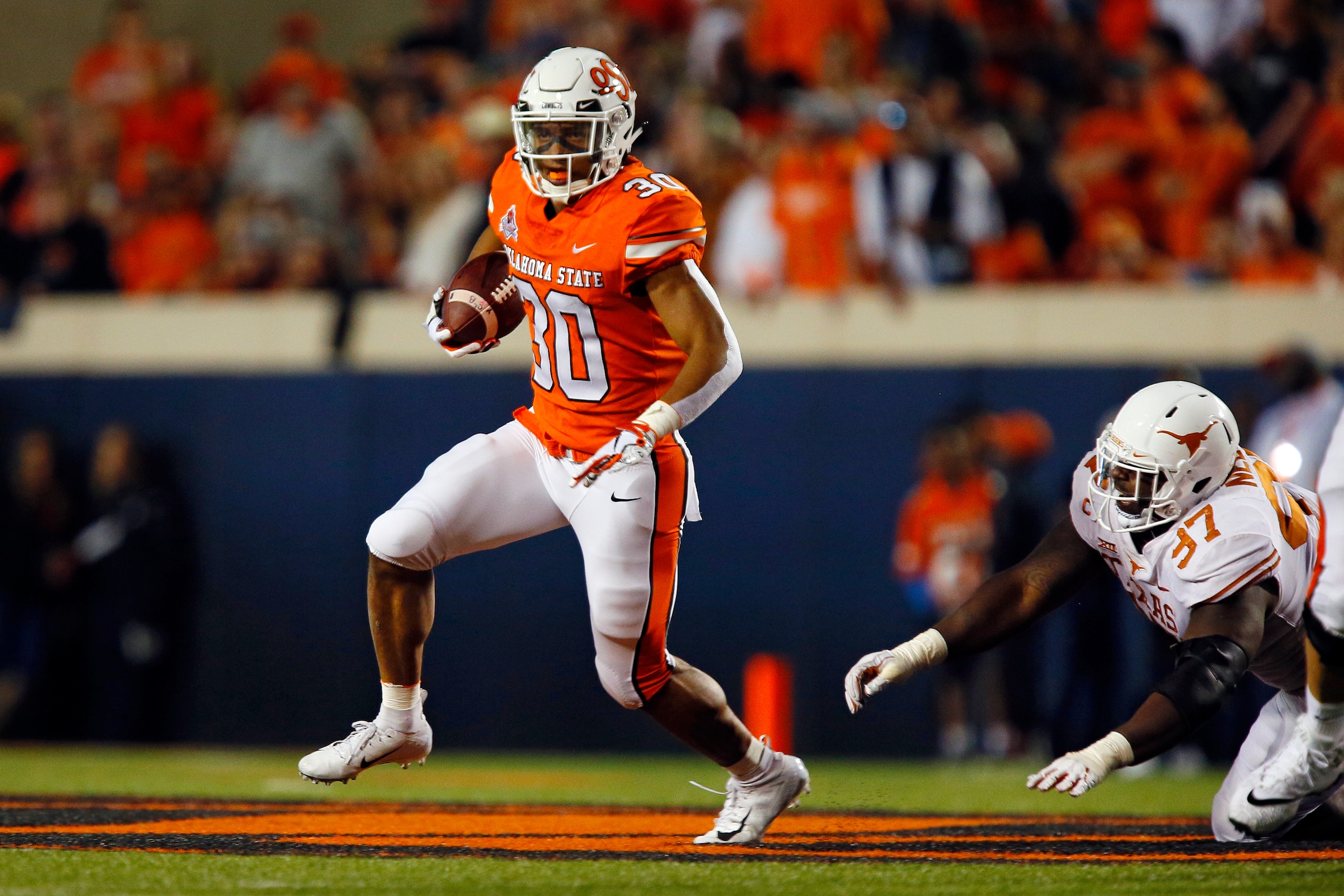 STILLWATER, OK - OCTOBER 27:  Running back Chuba Hubbard #30 of the Oklahoma State Cowboys runs against defensive lineman Chris Nelson #97 of the Texas Longhorns in the second quarter on October 27, 2018 at Boone Pickens Stadium in Stillwater, Oklahoma.  
