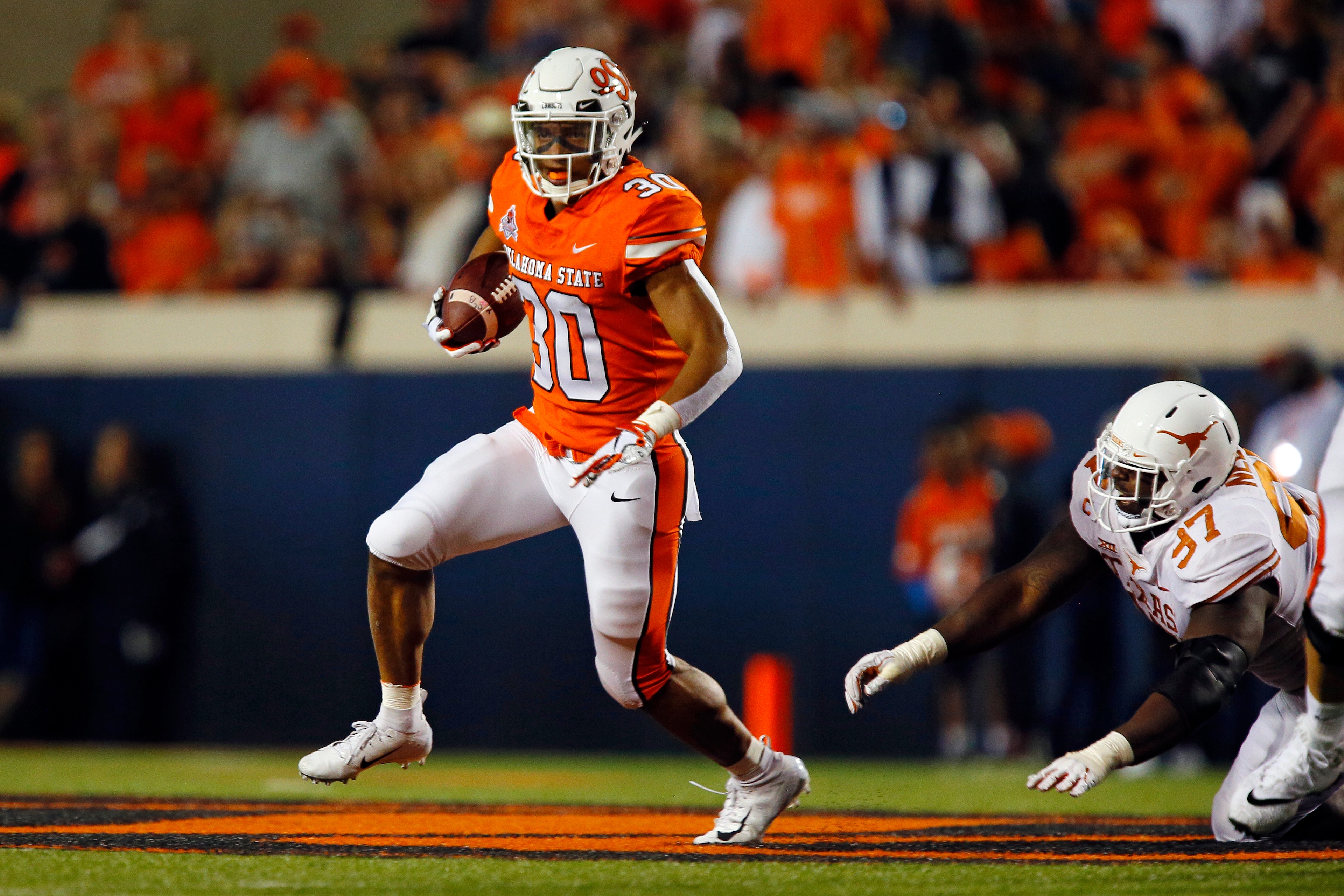 STILLWATER, OK - OCTOBER 27:  Running back Chuba Hubbard #30 of the Oklahoma State Cowboys runs against defensive lineman Chris Nelson #97 of the Texas Longhorns in the second quarter on October 27, 2018 at Boone Pickens Stadium in Stillwater, Oklahoma.  