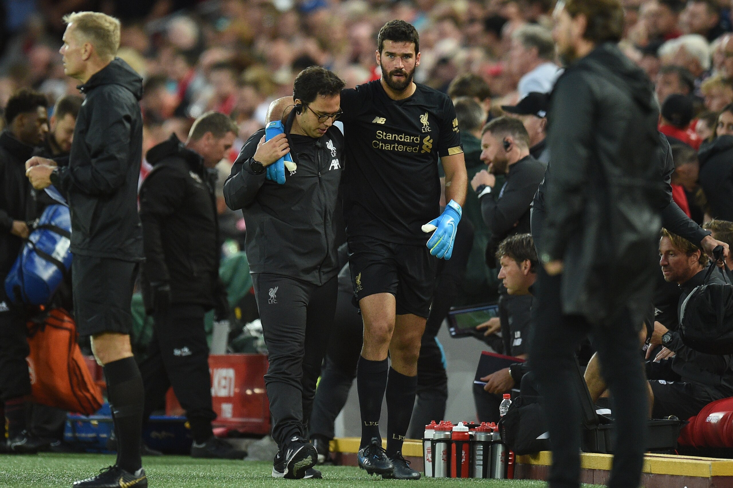Liverpool's Brazilian goalkeeper Alisson Becker (CR) is assisted off the field with an injury during the English Premier League football match between Liverpool and Norwich City at Anfield in Liverpool, north west England on August 9, 2019. (Photo by Oli 