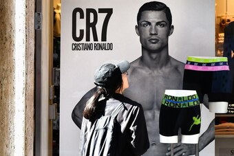 A passerby watches an advertising poster for an underwear brand, showing a picture of Juventus' Portuguese forward Cristiano Ronaldo in a shop window, on October 9, 2018 in downtown Rome. - Cristiano Ronaldo faces rape allegations after US police on Octob
