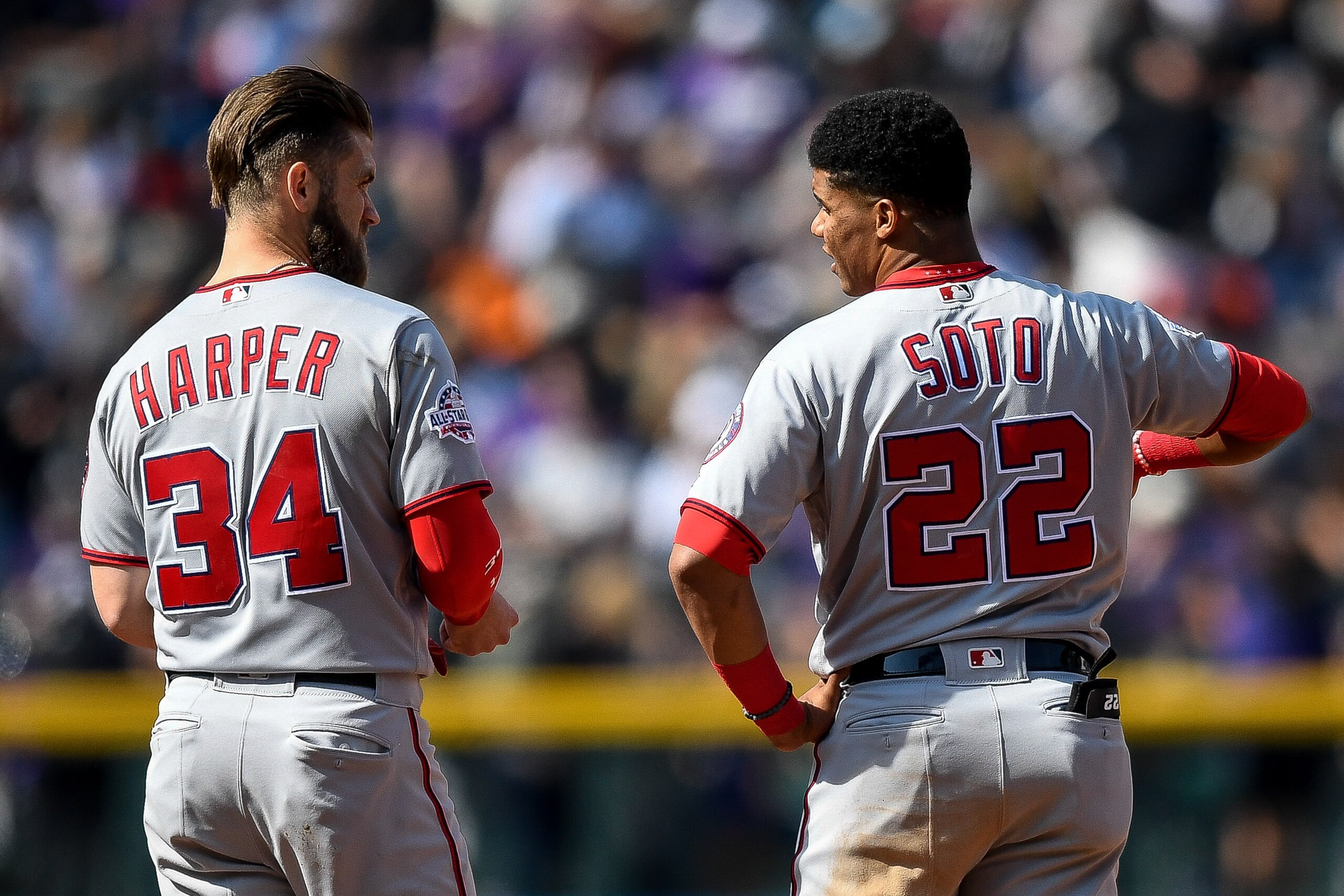 DENVER, CO - SEPTEMBER 30:  Bryce Harper #34 and Juan Soto #22 of the Washington Nationals have a word after Harper was stranded on the bases after the top of the fourth inning of a game against the Colorado Rockies at Coors Field on September 30, 2018 in