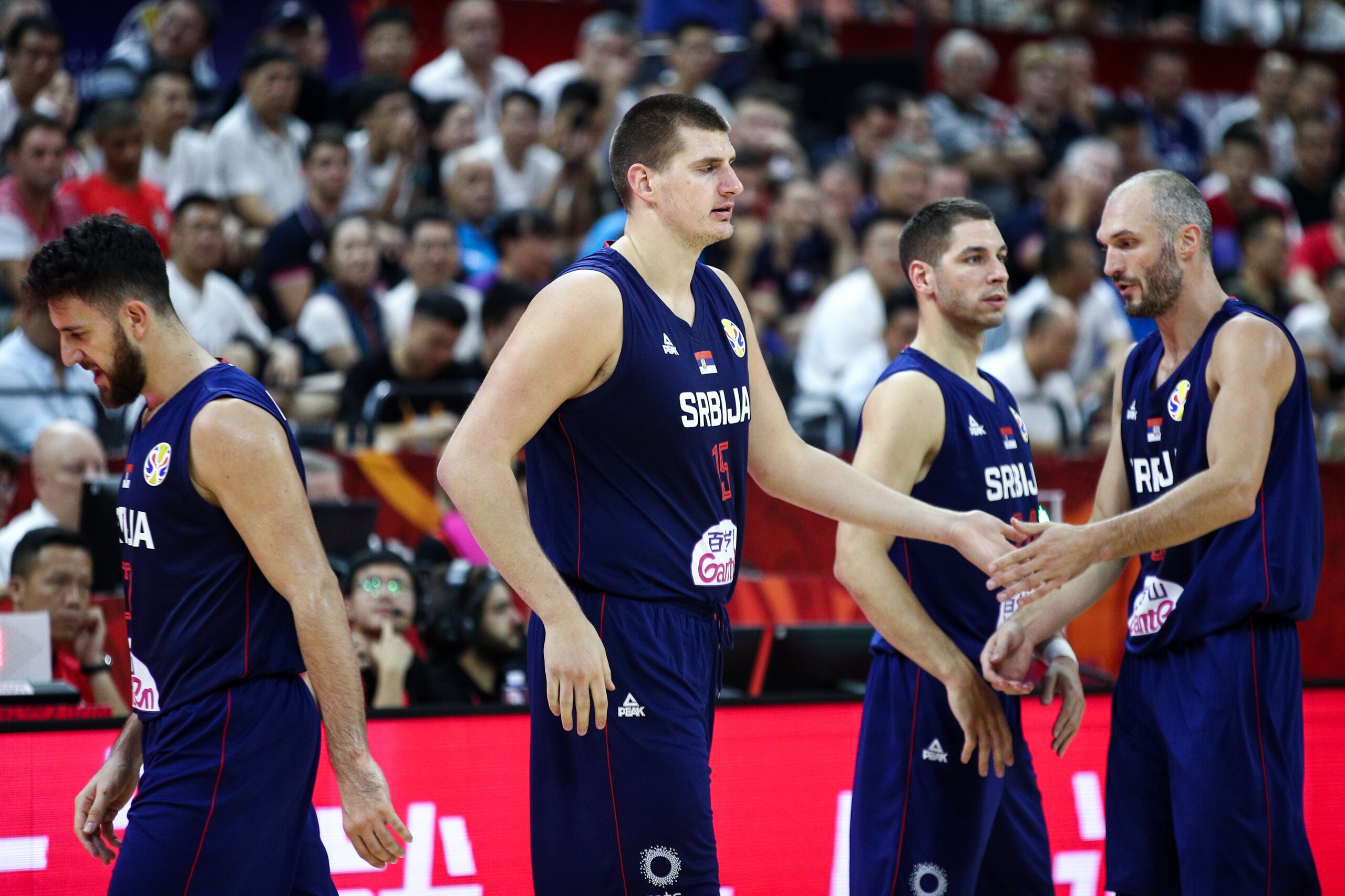 FOSHAN, CHINA - AUGUST 31: #15 Nikola Jokic of the Serbia National Team cheers with team mates #5 Marko Simonovic and #22 Vasilije Micic against the Angola National Team during the 1st round of 2019 FIBA World Cup at GBA International Sports and Cultural FOSHAN, CHINA - AUGUST 31: #15 Nikola Jokic of the Serbia National Team cheers with team mates #5 Marko Simonovic and #22 Vasilije Micic against the Angola National Team during the 1st round of 2019 FIBA World Cup at GBA International Sports and Cultural