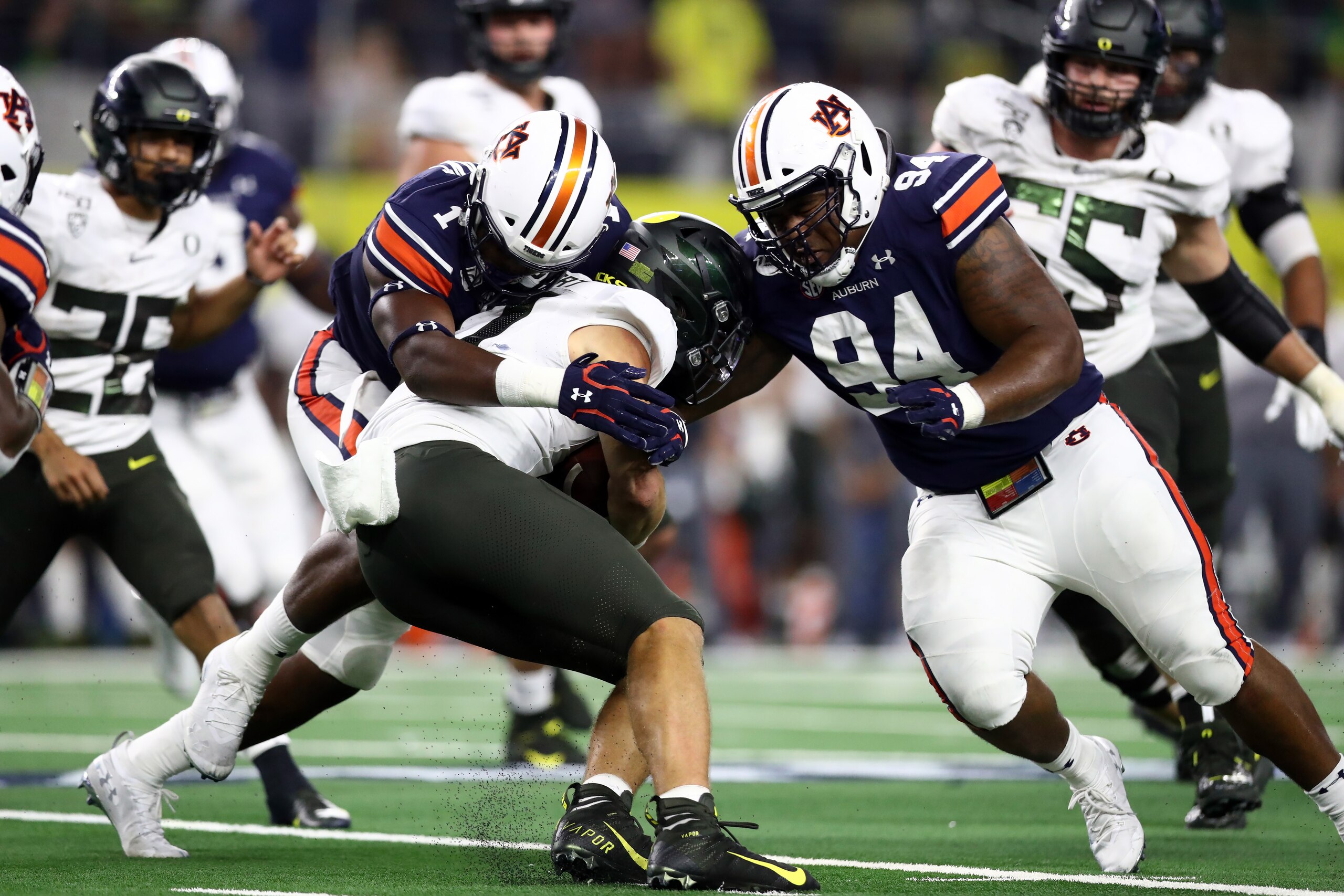 ARLINGTON, TEXAS - AUGUST 31:  Justin Herbert #10 of the Oregon Ducks is tackled by Big Kat Bryant #1 and Tyrone Truesdell #94 of the Auburn Tigers during the Advocare Classic at AT&T Stadium on August 31, 2019 in Arlington, Texas. (Photo by Ronald Martin