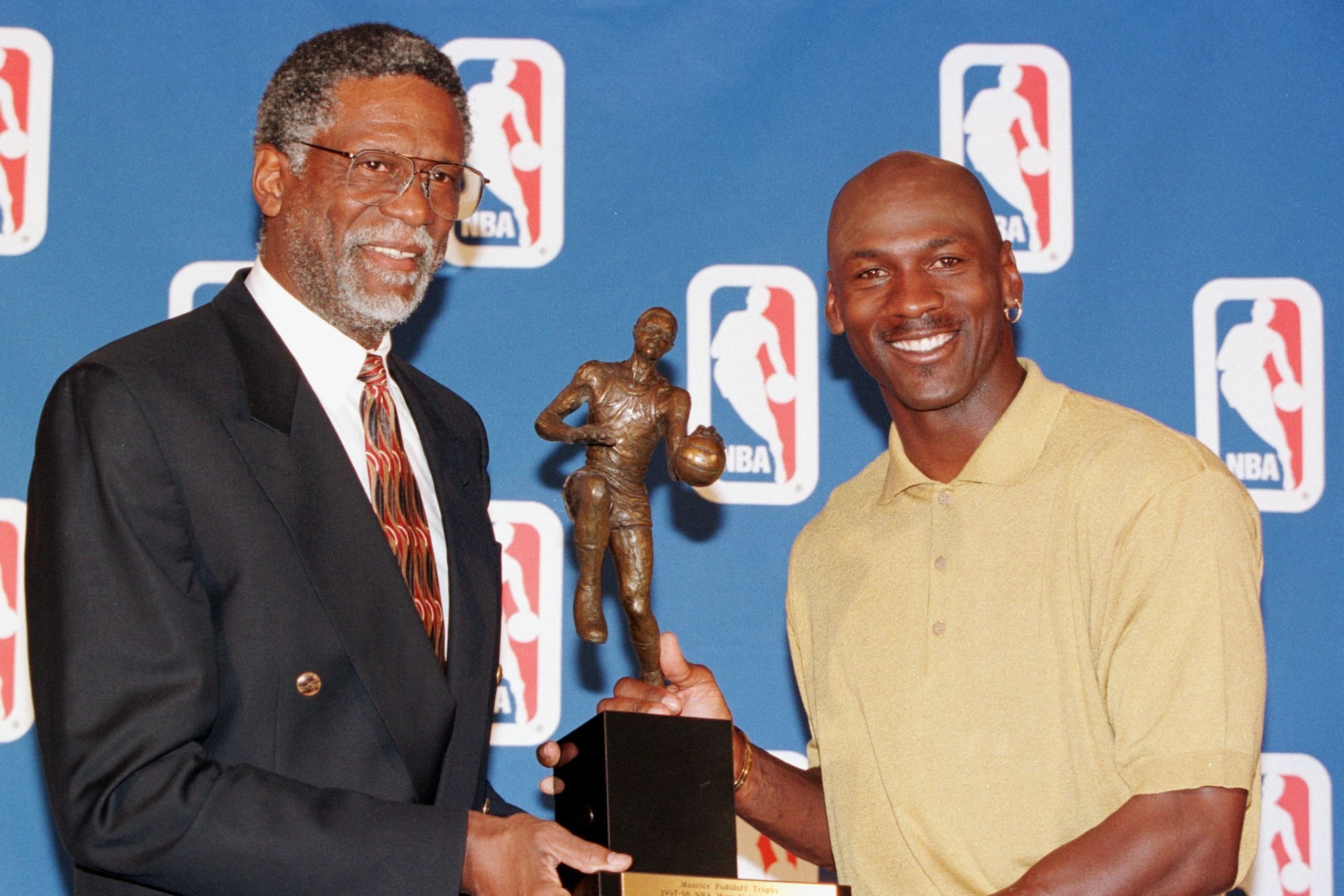 NORTHBROOK, UNITED STATES:  Former NBA great Bill Russell (L) hands Michael Jordan (R) of the Chicago Bulls his fifth Maurice Podoloff Most Valuable Player Trophy for the 1997-98 season 18 May, at a press conference at the Sheraton North Shore Hotel in No