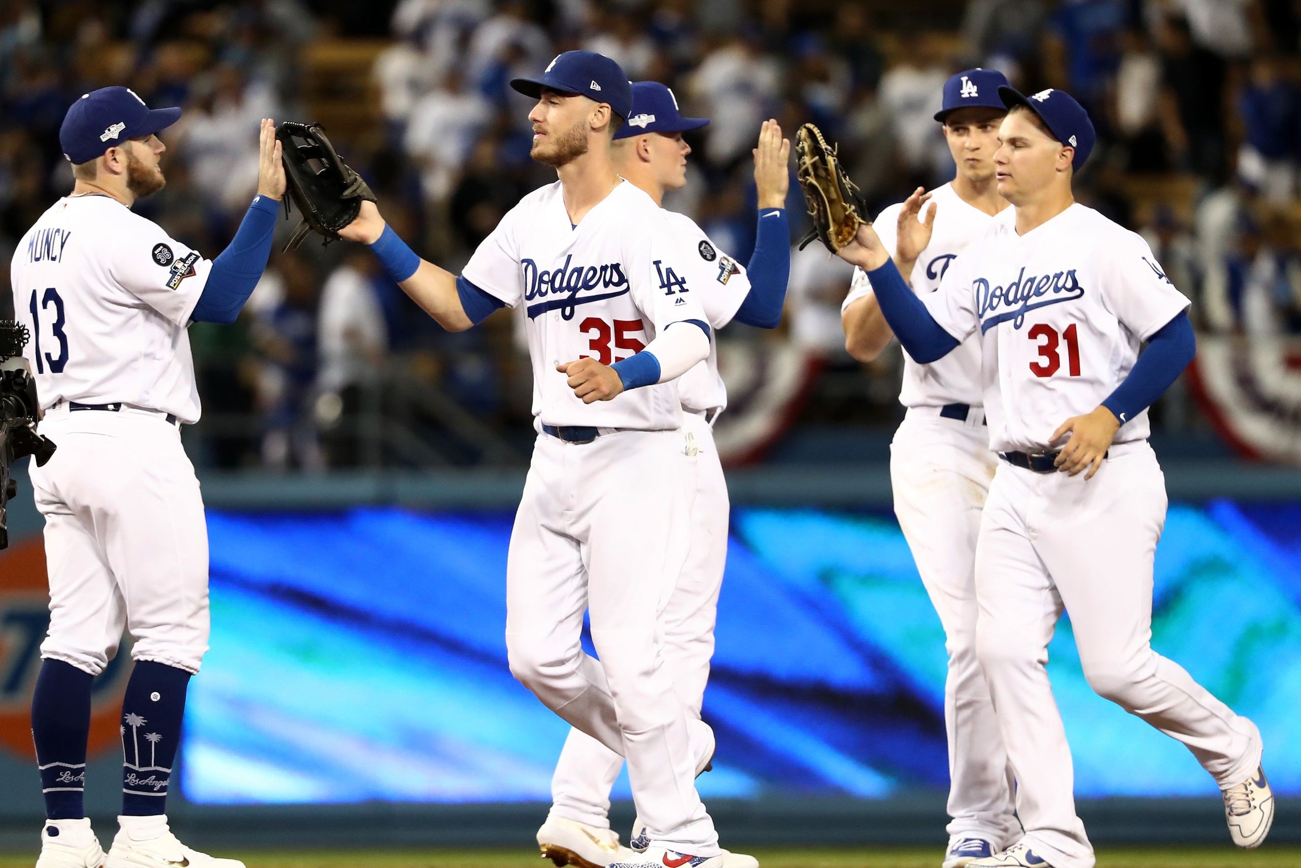 LOS ANGELES, CALIFORNIA - OCTOBER 03: (L-R) Max Muncy #13, Cody Bellinger #35 and Joc Pederson #31 of the Los Angeles Dodgers celebrate defeating the Washington Nationals 6-0 in game one of the National League Division Series at Dodger Stadium on October 