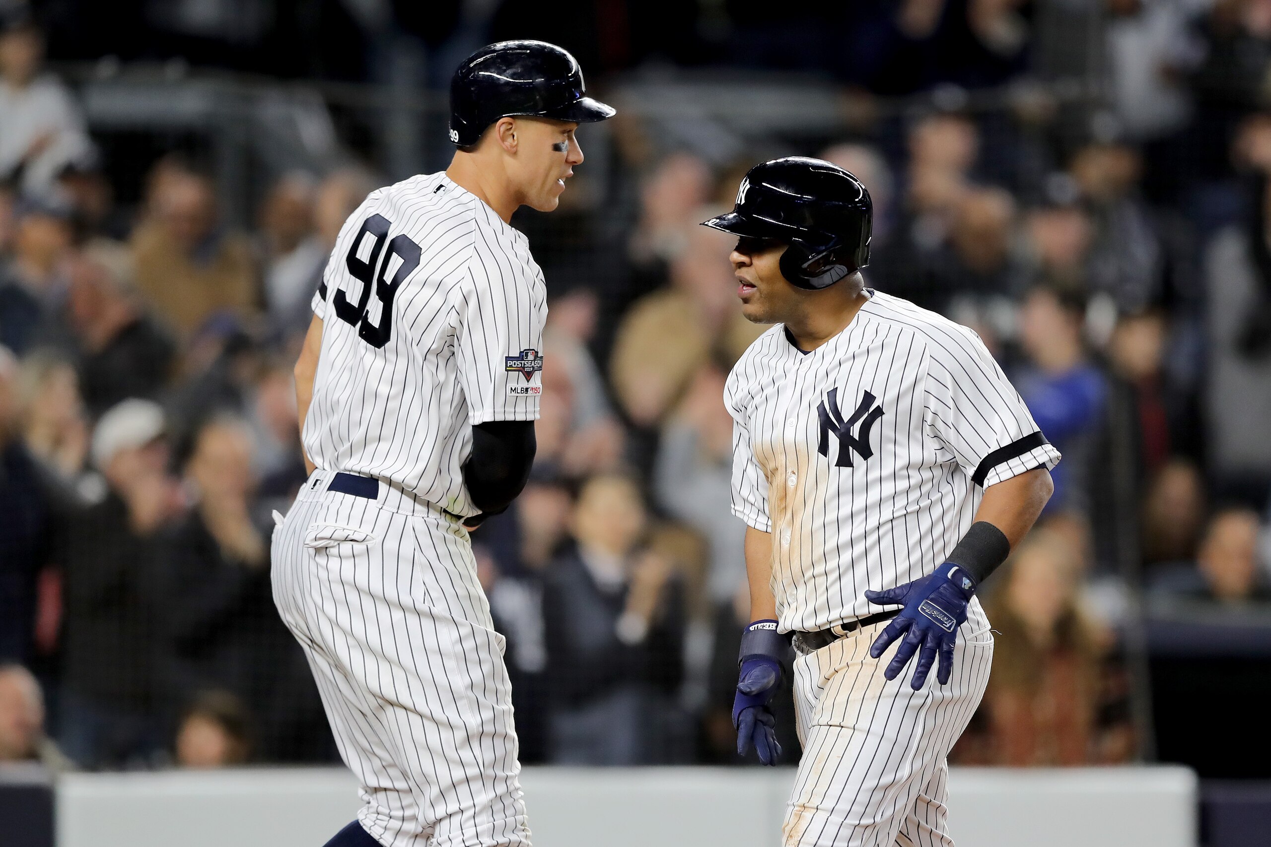 NEW YORK, NEW YORK - OCTOBER 04: Aaron Judge #99 and Edwin Encarnacion #30 of the New York Yankees celebrate after scoring off of a RBI single hit by Gleyber Torres #25 against Jose Berrios #17 of the Minnesota Twins during the third inning in game one of