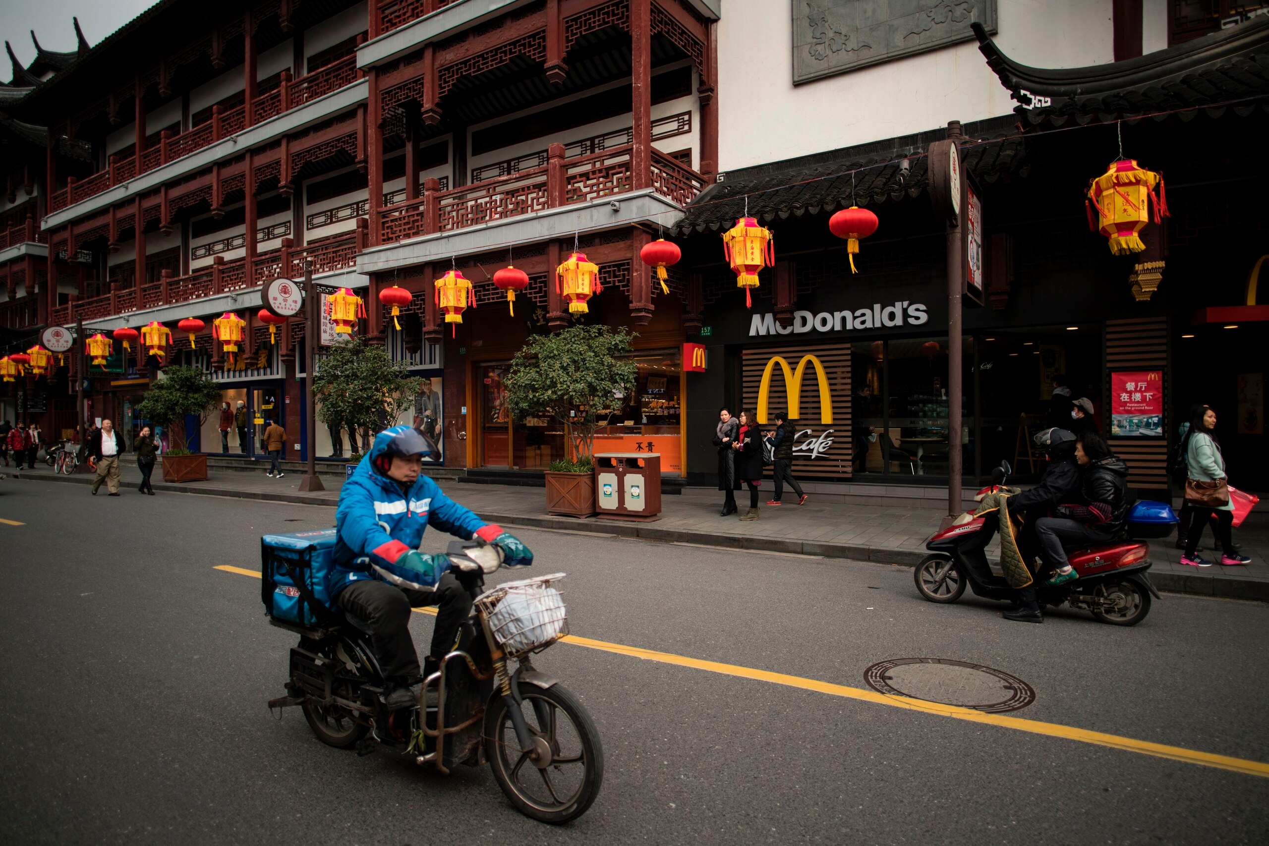 A man drives his scooter past a McDonald's fast food restaurant in Shanghai on January 9, 2017. 
US fast-food giant McDonalds will sell a controlling stake in its China and Hong Kong business for up to 2.08 billion USD to a consortium including state-owne