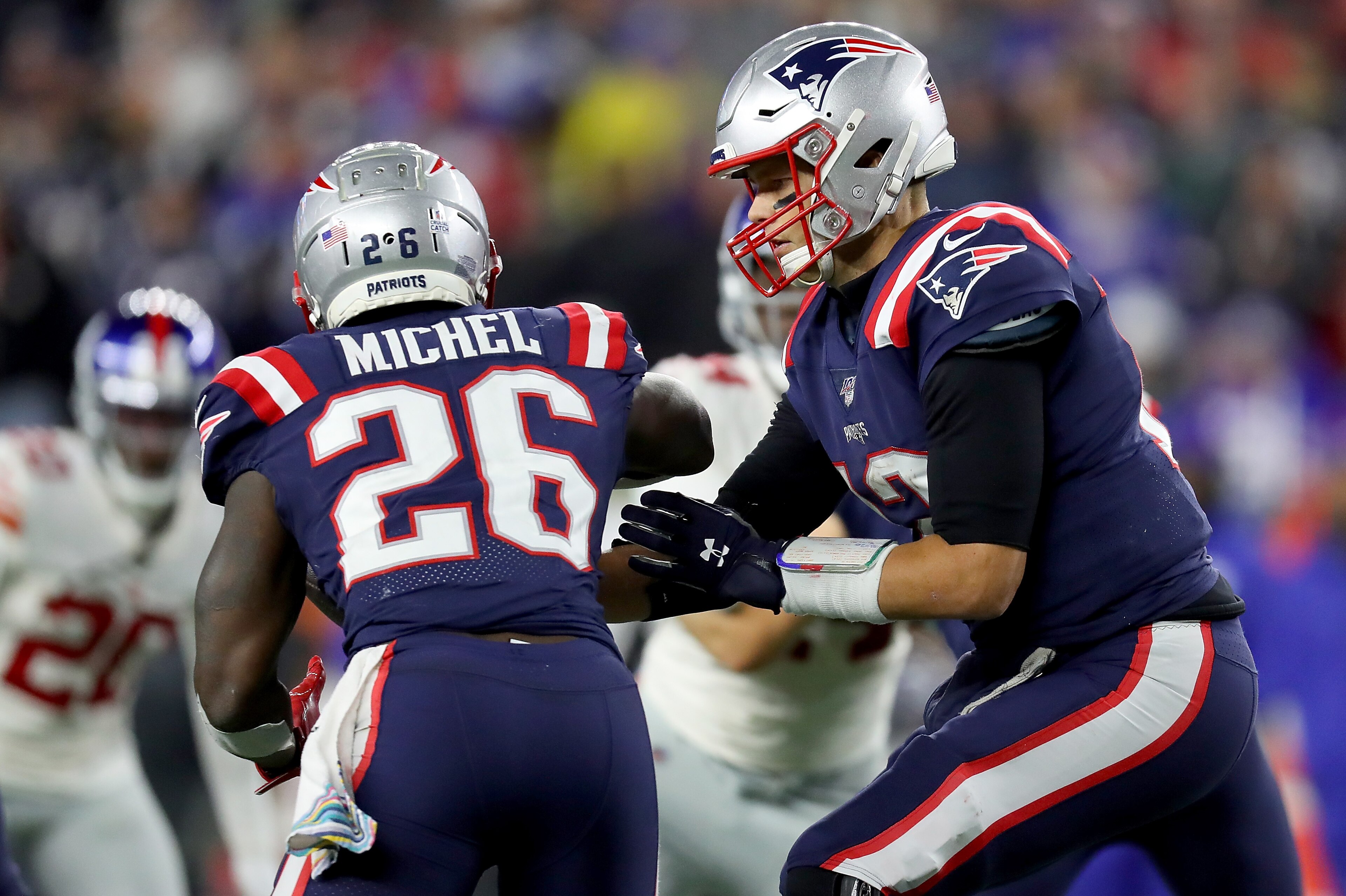 FOXBOROUGH, MASSACHUSETTS - OCTOBER 10: Tom Brady #12 of the New England Patriots hands the ball off to Sony Michel #26 against the New York Giants during the fourth quarter in the game at Gillette Stadium on October 10, 2019 in Foxborough, Massachusetts.