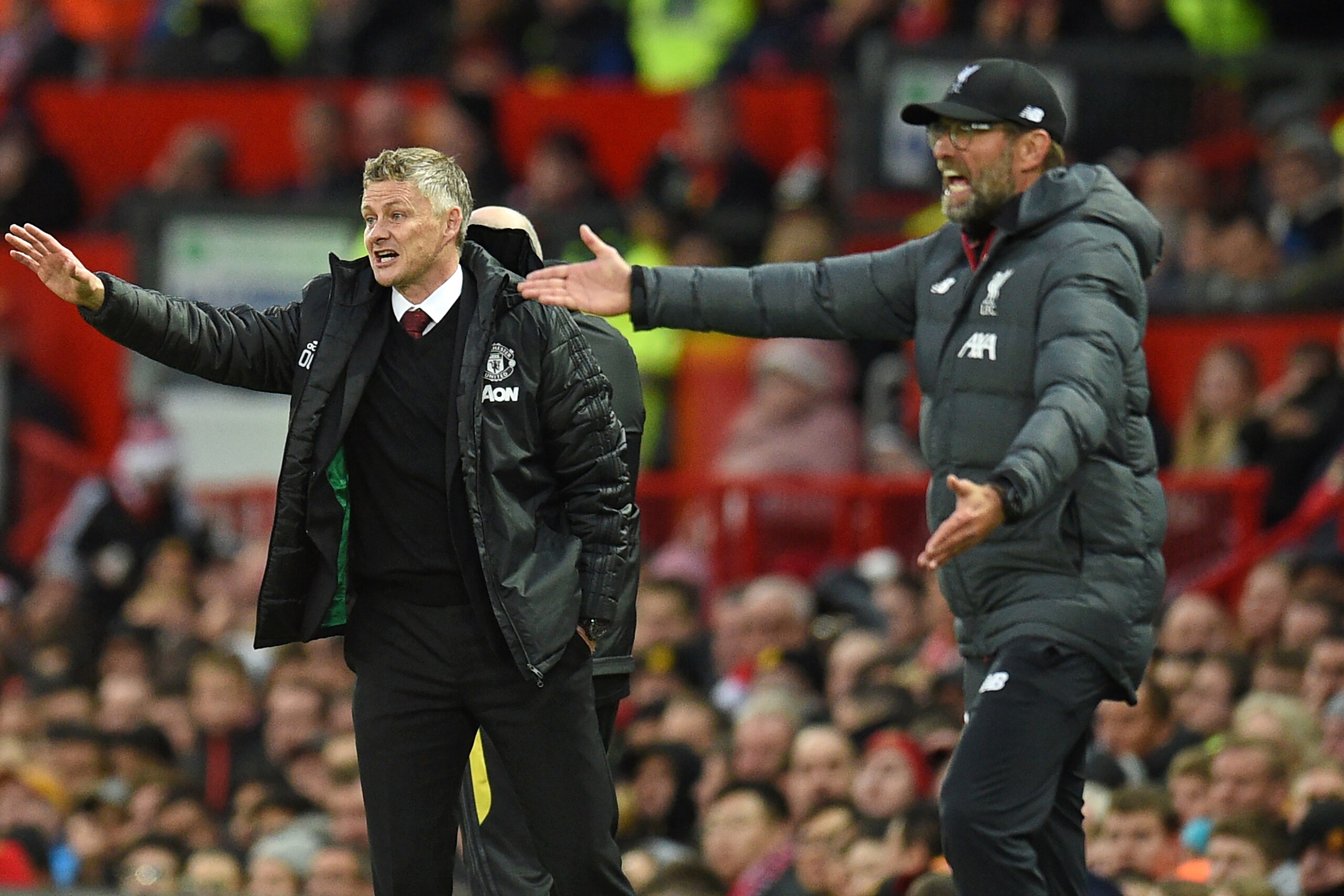 Manchester United's Norwegian manager Ole Gunnar Solskjaer (L) and Liverpool's German manager Jurgen Klopp (R) gesture on the touchline during the English Premier League football match between Manchester United and Liverpool at Old Trafford in Manchester,