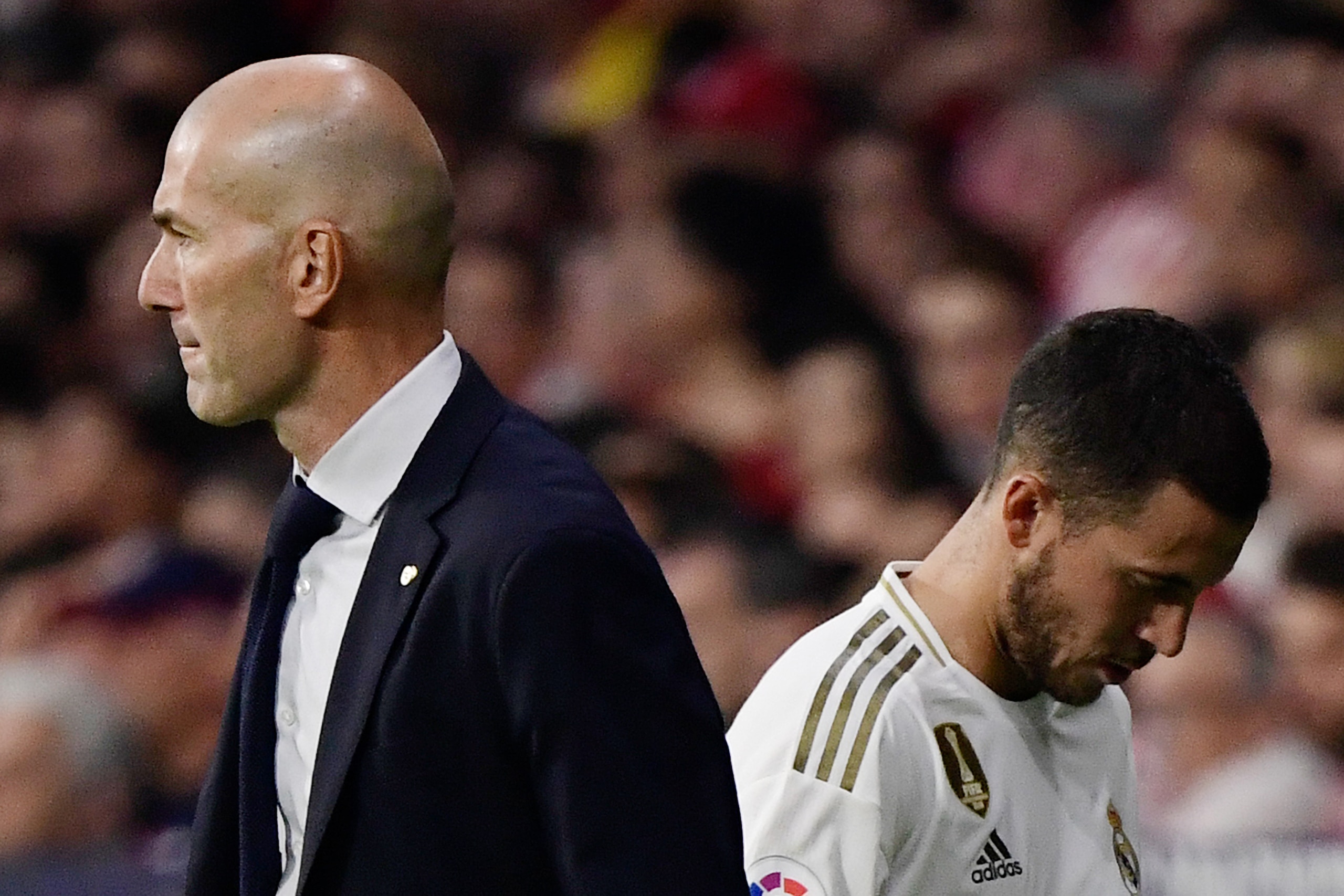 Real Madrid's Belgian forward Eden Hazard (R) walks past Real Madrid's French coach Zinedine Zidane as he leaves the pitch during the Spanish league football match between Club Atletico de Madrid and Real Madrid CF at the Wanda Metropolitano stadium in Ma