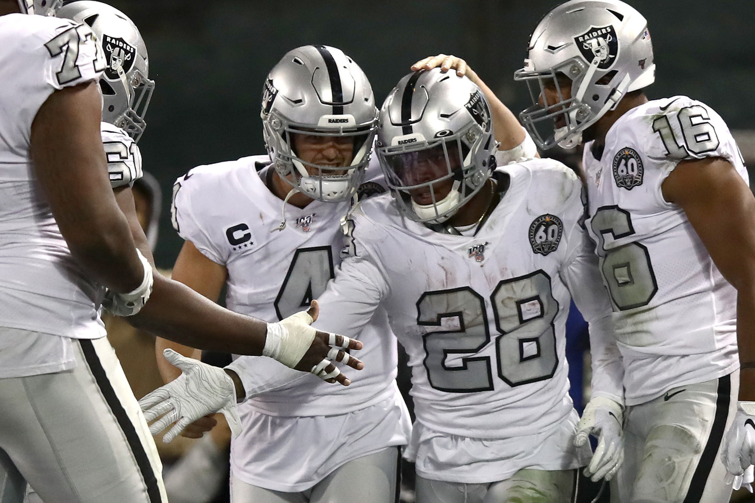 OAKLAND, CALIFORNIA - NOVEMBER 07:   Josh Jacobs #28 of the Oakland Raiders is congratulated by teammates including Derek Carr #4 after he ran the ball in for the winning touchdown against the Los Angeles Chargers in the fourth quarter at RingCentral Coli