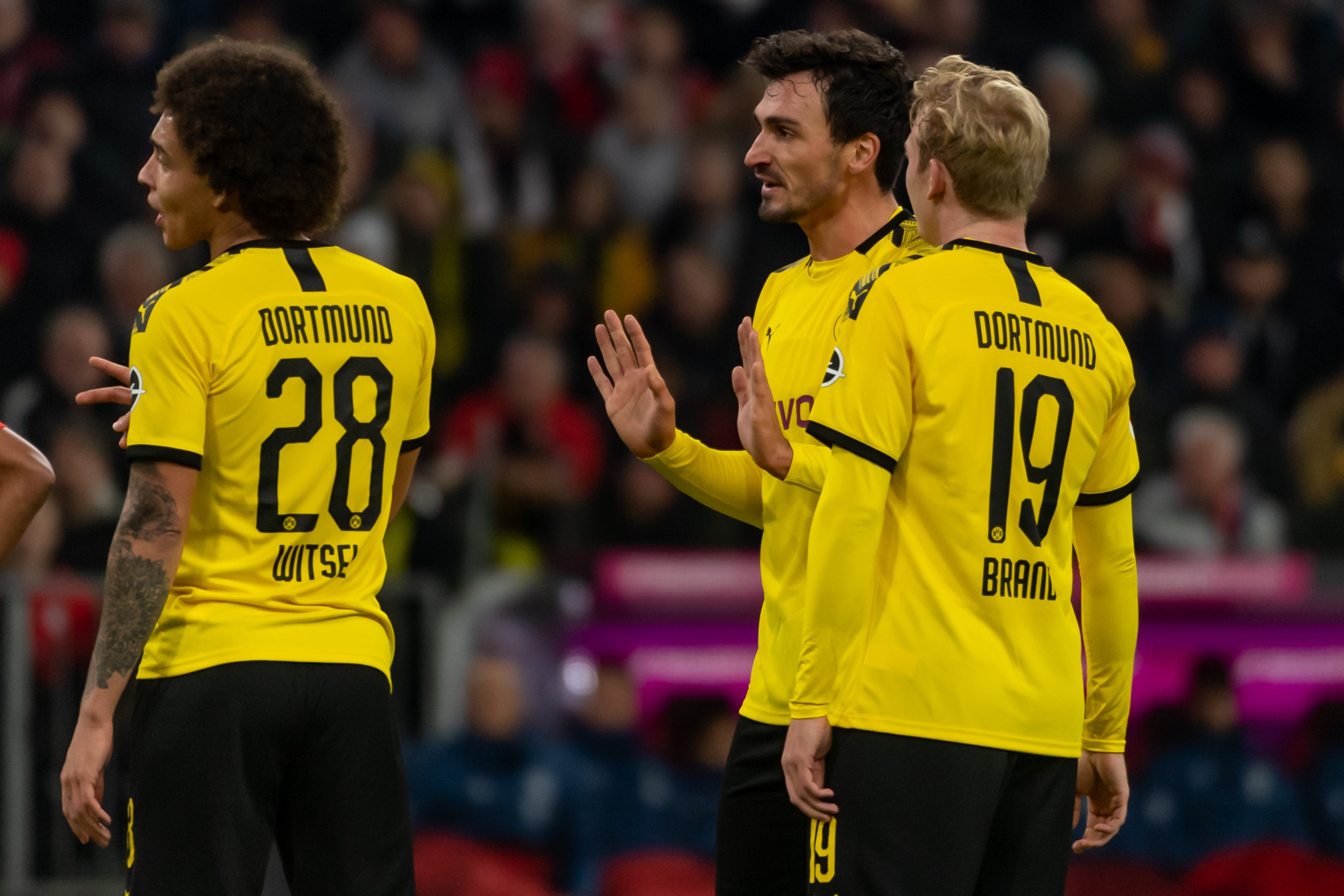 MUNICH, GERMANY - NOVEMBER 09: Axel Witsel of Borussia Dortmund speaks with Mats Hummels of Borussia Dortmund and Julian Brandt of Borussia Dortmund during the Bundesliga match between FC Bayern Muenchen and Borussia Dortmund at Allianz Arena on November 