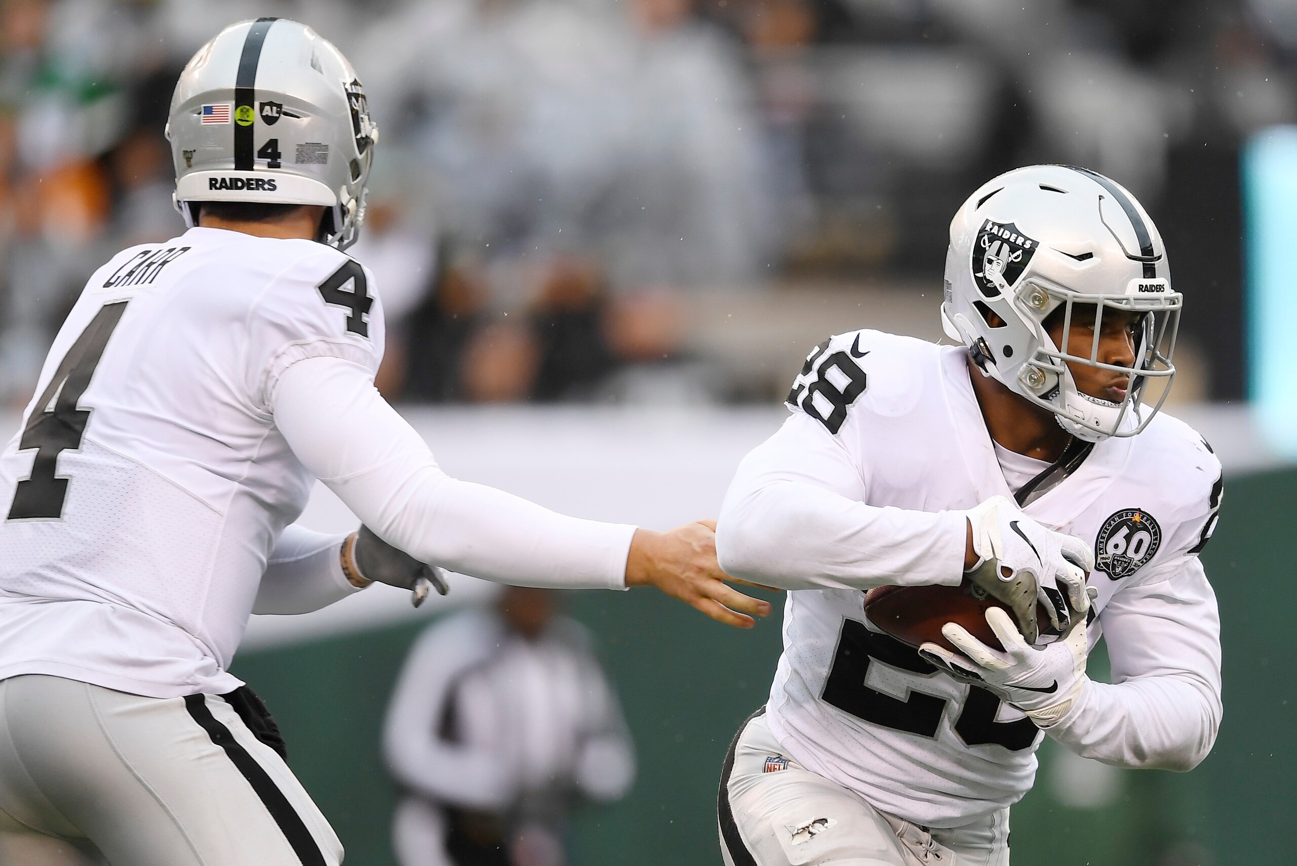 EAST RUTHERFORD, NEW JERSEY - NOVEMBER 24: Running back Josh Jacobs #28 of the Oakland Raiders takes the handoff from quarterback Derek Carr #4 during the first half of the game against the New York Jets at MetLife Stadium on November 24, 2019 in East Rut