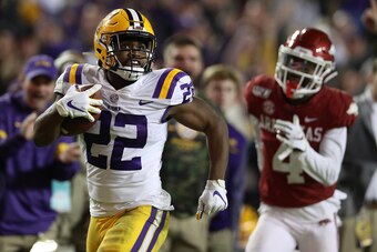 BATON ROUGE, LOUISIANA - NOVEMBER 23: Clyde Edwards-Helaire #22 of the LSU Tigers avoids a tackle by Jarques McClellion #4 of the Arkansas Razorbacks to score a touchdown at Tiger Stadium on November 23, 2019 in Baton Rouge, Louisiana. (Photo by Chris Gra