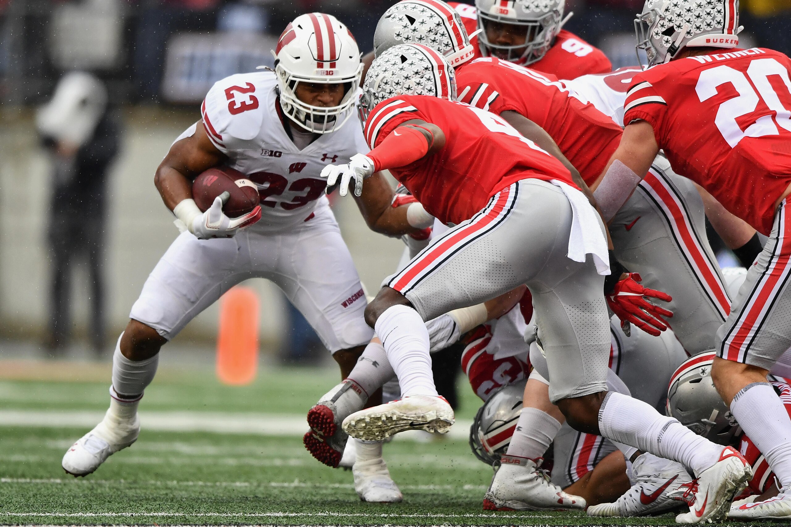 COLUMBUS, OH - OCTOBER 26:  Jonathan Taylor #23 of the Wisconsin Badgers looks for running room as Jordan Fuller #4 of the Ohio State Buckeyes closes in during the second quarter at Ohio Stadium on October 26, 2019 in Columbus, Ohio.  (Photo by Jamie Saba