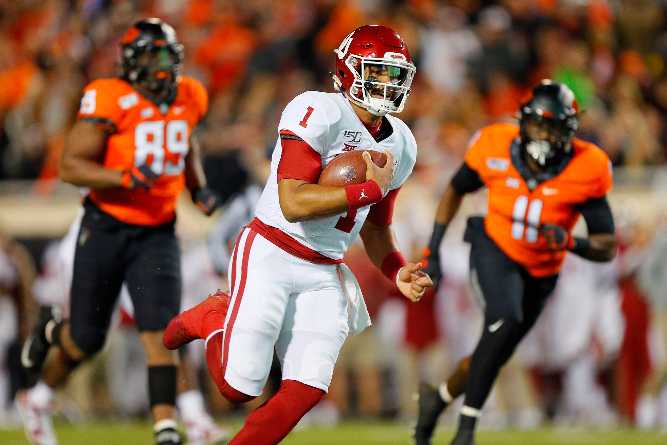 STILLWATER, OK - NOVEMBER 30: Quarterback Jalen Hurts #1 of the Oklahoma Sooners breaks free for a 28-yard touchdown run against defensive end Tyler Lacy #89 and linebacker Amen Ogbongbemiga #11 of the Oklahoma State Cowboys in the first quarter on Novem STILLWATER, OK - NOVEMBER 30: Quarterback Jalen Hurts #1 of the Oklahoma Sooners breaks free for a 28-yard touchdown run against defensive end Tyler Lacy #89 and linebacker Amen Ogbongbemiga #11 of the Oklahoma State Cowboys in the first quarter on Novem
