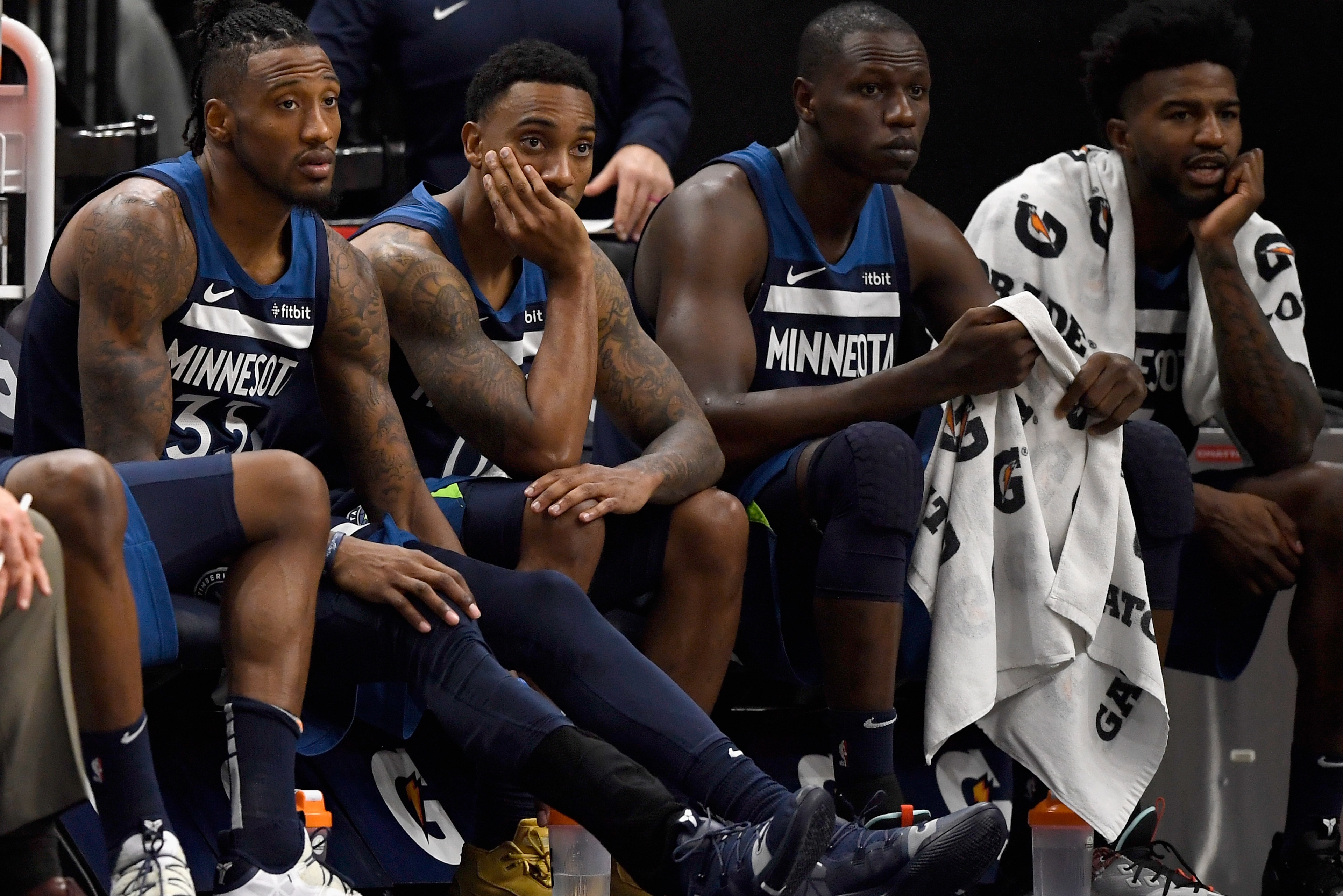 MINNEAPOLIS, MINNESOTA - NOVEMBER 04: (L-R) Robert Covington #33, Jeff Teague #0, Gorgui Dieng #5 and Jordan Bell #7 of the Minnesota Timberwolves look on from the bench in the final minutes of the game against the Milwaukee Bucks at Target Center on Nove