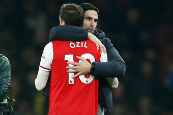 Arsenal's Spanish head coach Mikel Arteta (R) embraces Arsenal's German midfielder Mesut Ozil (L) on the pitch after the English Premier League football match between Arsenal and Manchester United at the Emirates Stadium in London on January 1, 2020. - Ar