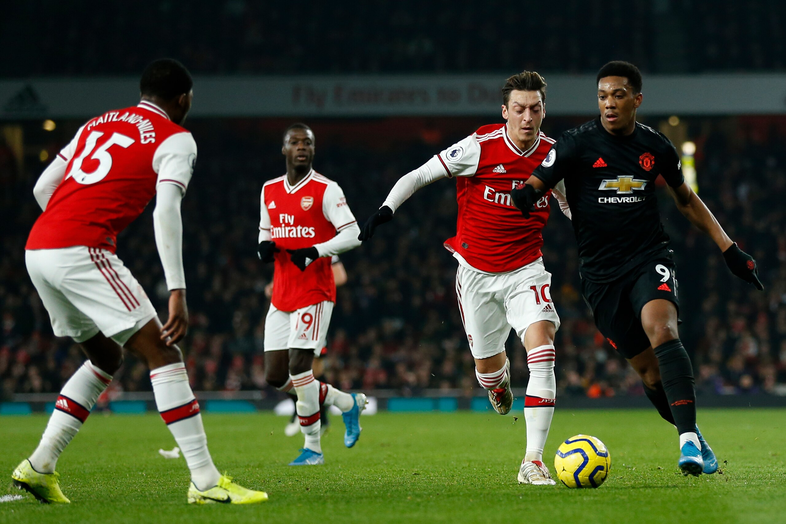 Manchester United's French striker Anthony Martial (R) vies with Arsenal's German midfielder Mesut Ozil (2nd R) ans Arsenal's English midfielder Ainsley Maitland-Niles (L) during the English Premier League football match between Arsenal and Manchester Uni