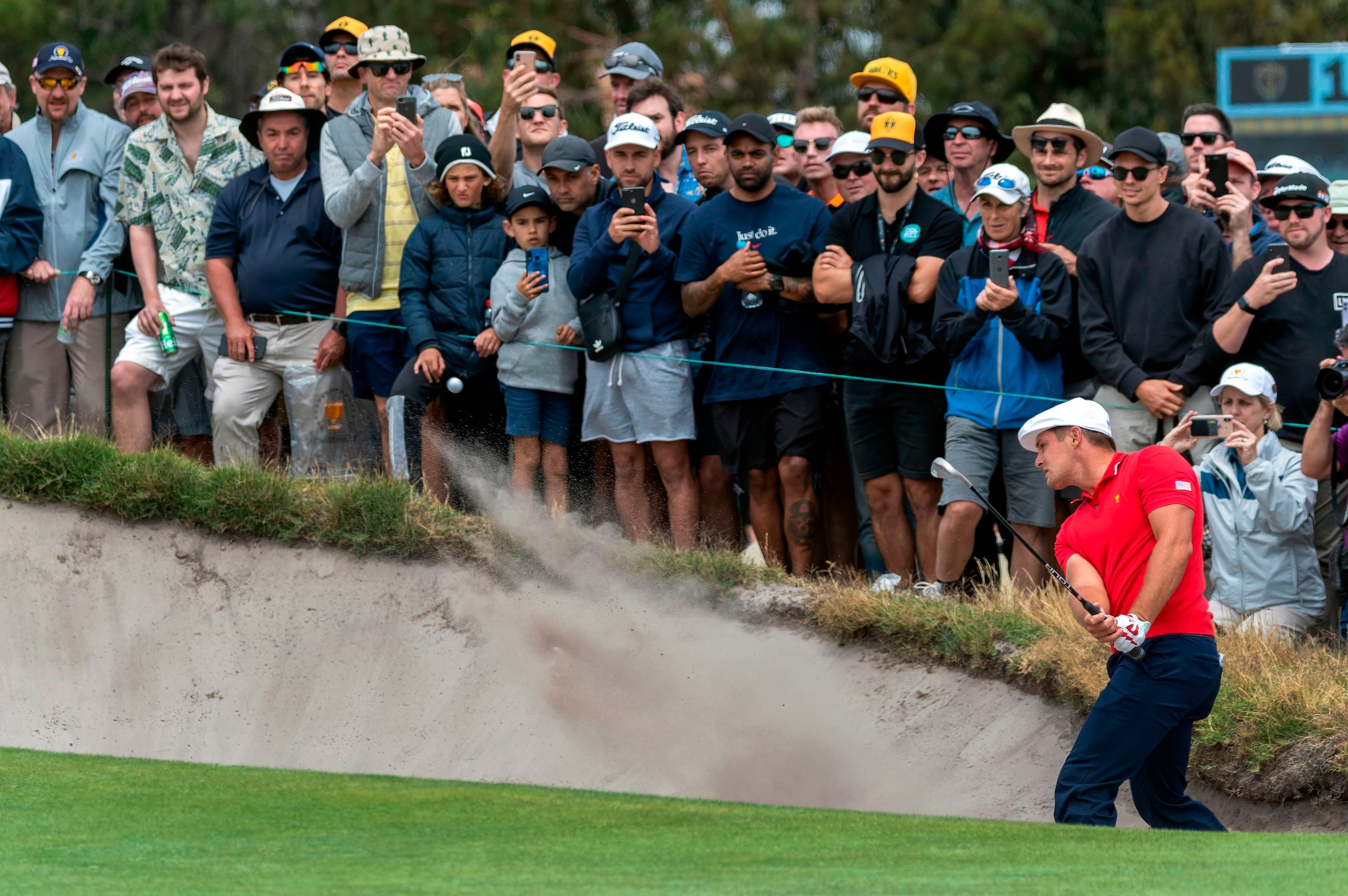 US player Bryson DeChambeau (R) plays out of the bunker to the 17th hole on the last day of the Presidents Cup golf tournament in Melbourne on December 15, 2019. (Photo by SIMON BAKER / AFP) / -- IMAGE RESTRICTED TO EDITORIAL USE - STRICTLY NO COMMERCIAL 