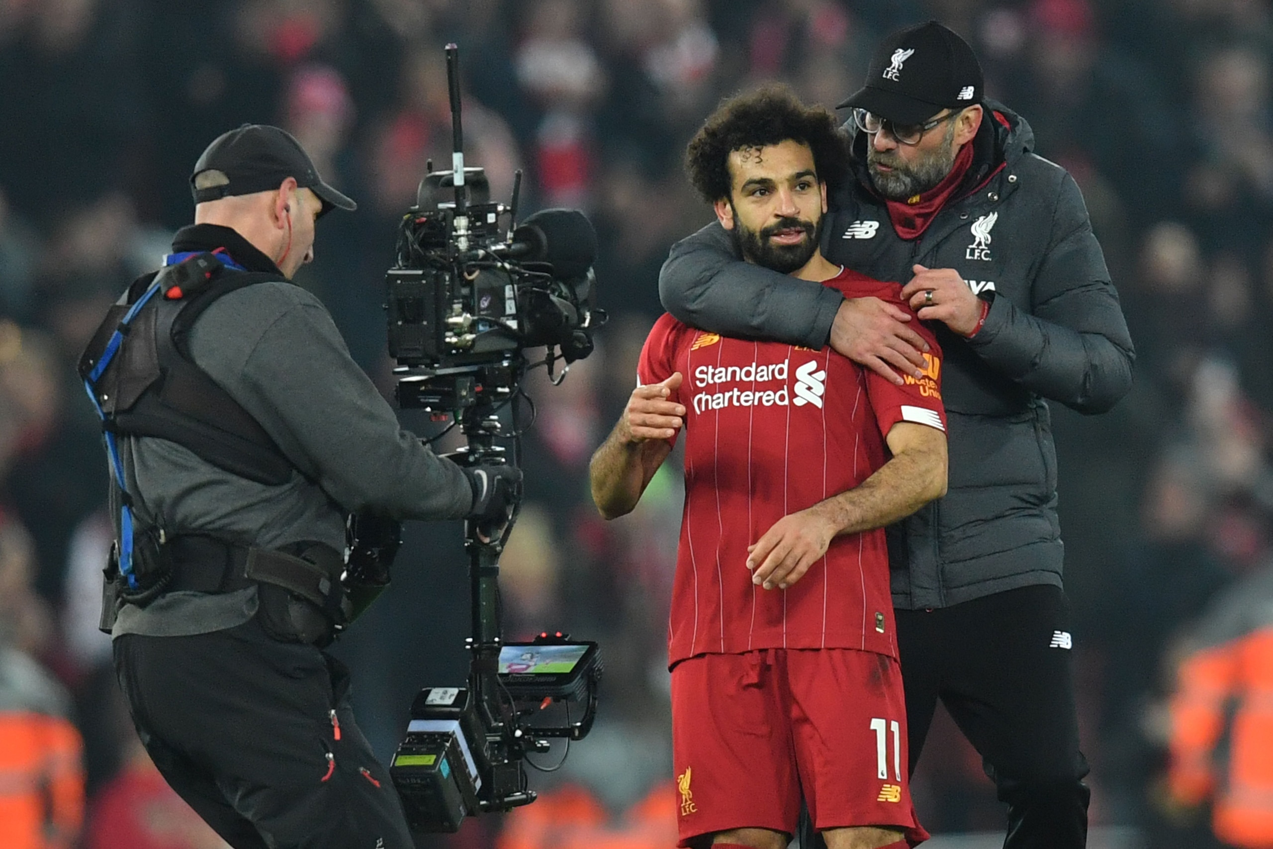 A cameraman films Liverpool's German manager Jurgen Klopp (R) embracing Liverpool's Egyptian midfielder Mohamed Salah (C) at the end of the English Premier League football match between Liverpool and Manchester United at Anfield stadium in Liverpool, nort A cameraman films Liverpool's German manager Jurgen Klopp (R) embracing Liverpool's Egyptian midfielder Mohamed Salah (C) at the end of the English Premier League football match between Liverpool and Manchester United at Anfield stadium in Liverpool, nort