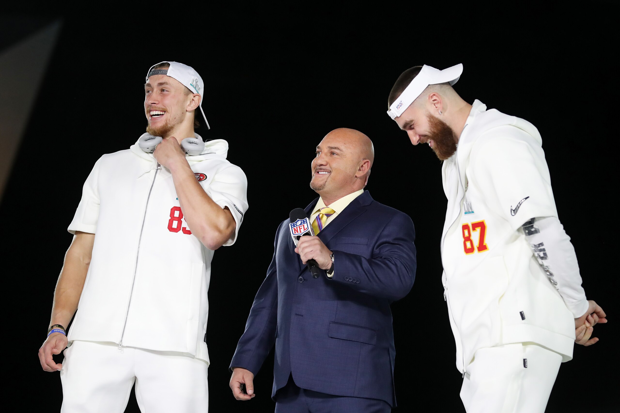 MIAMI, FLORIDA - JANUARY 27: Tight end George Kittle #85 of the San Francisco 49ers and tight end Travis Kelce #87 of the Kansas City Chiefs speak to sportscaster Jay Glazer during Super Bowl Opening Night presented by BOLT24 at Marlins Park on January 27