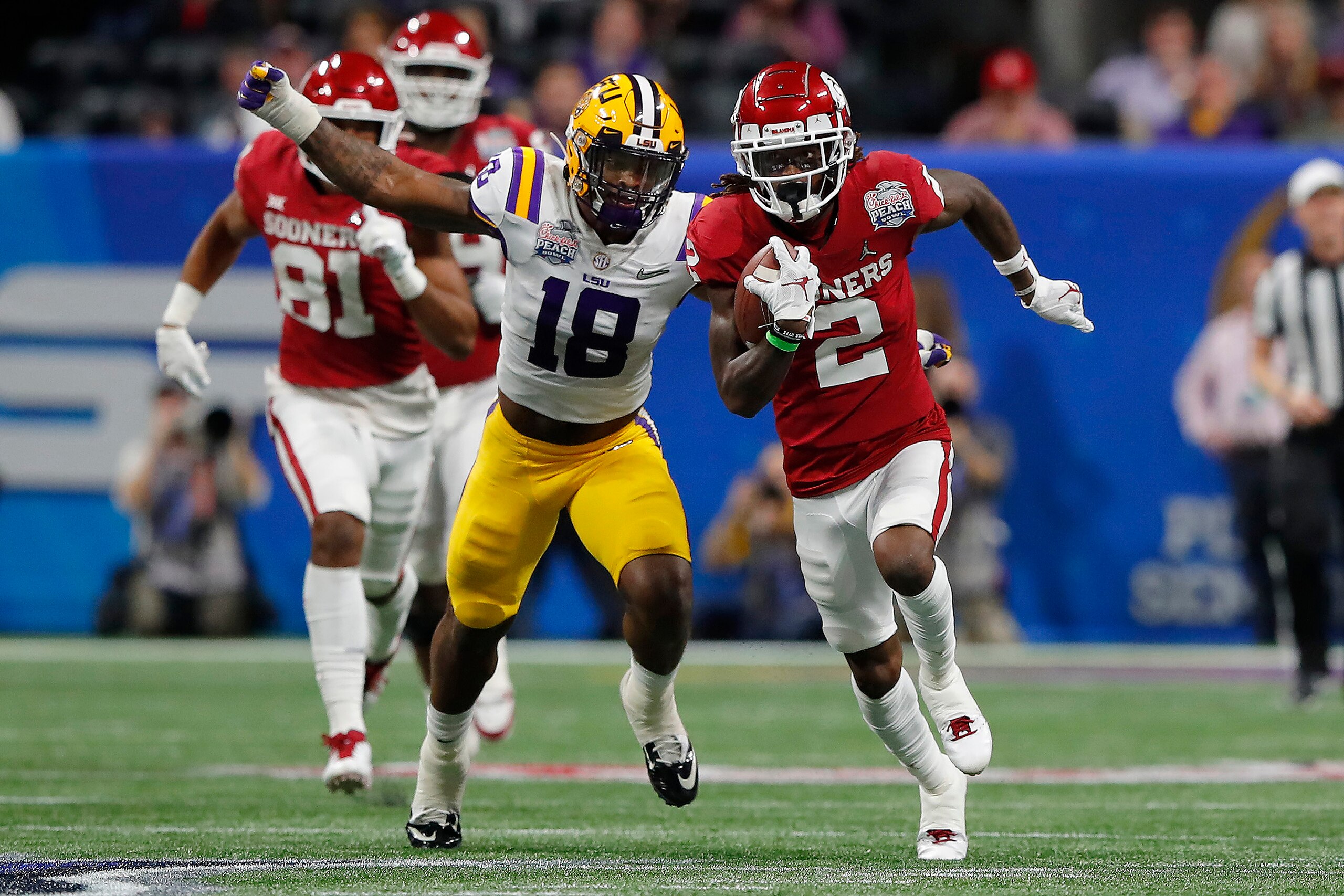 ATLANTA, GEORGIA - DECEMBER 28: Wide receiver CeeDee Lamb #2 of the Oklahoma Sooners carries the ball against linebacker K'Lavon Chaisson #18 of the LSU Tigers during the Chick-fil-A Peach Bowl at Mercedes-Benz Stadium on December 28, 2019 in Atlanta, Geo