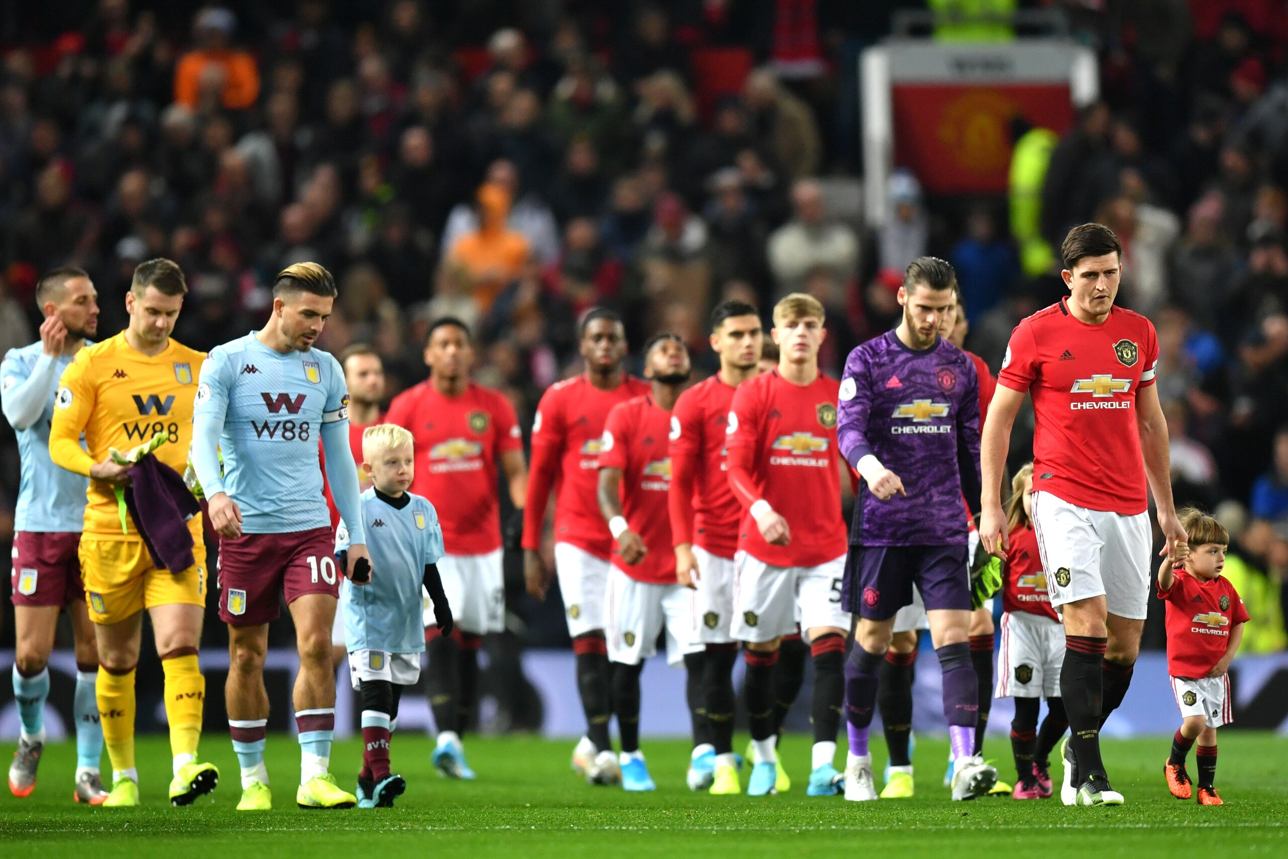 MANCHESTER, ENGLAND - DECEMBER 01: Jack Grealish of Aston Villa and Harry Maguire of Manchester United lead their teams onto the pitch ahead of the Premier League match between Manchester United and Aston Villa at Old Trafford on December 01, 2019 in Manc