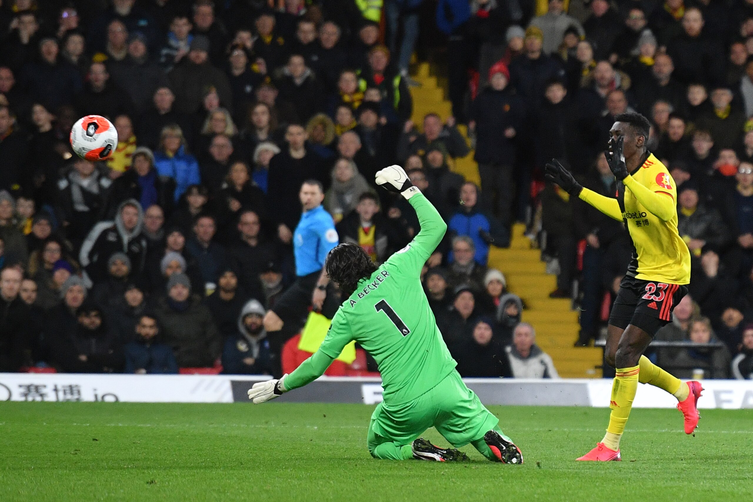 Watford's Senegalese midfielder Ismaila Sarr (R) scores his team's second goal past Liverpool's Brazilian goalkeeper Alisson Becker during the English Premier League football match between Watford and Liverpool at Vicarage Road Stadium in Watford, north o