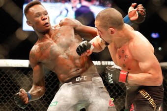 Robert Whittaker of Australia (R) punches Israel Adesanya of New Zealand (L) during the middleweight title bout of the UFC 243 fight night in Melbourne on October 6, 2019. (Photo by ASANKA BRENDON RATNAYAKE / AFP) / -- IMAGE RESTRICTED TO EDITORIAL USE - 