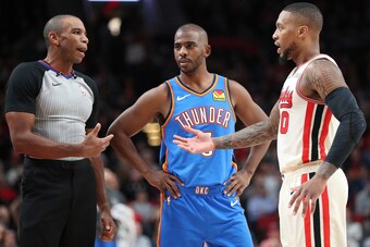 PORTLAND, OREGON - NOVEMBER 27: Chris Paul #3 of the Oklahoma City Thunder and Damian Lillard #0 of the Portland Trail Blazers have a conversation with an official in the third quarter during their game at Moda Center on November 27, 2019 in Portland, Ore