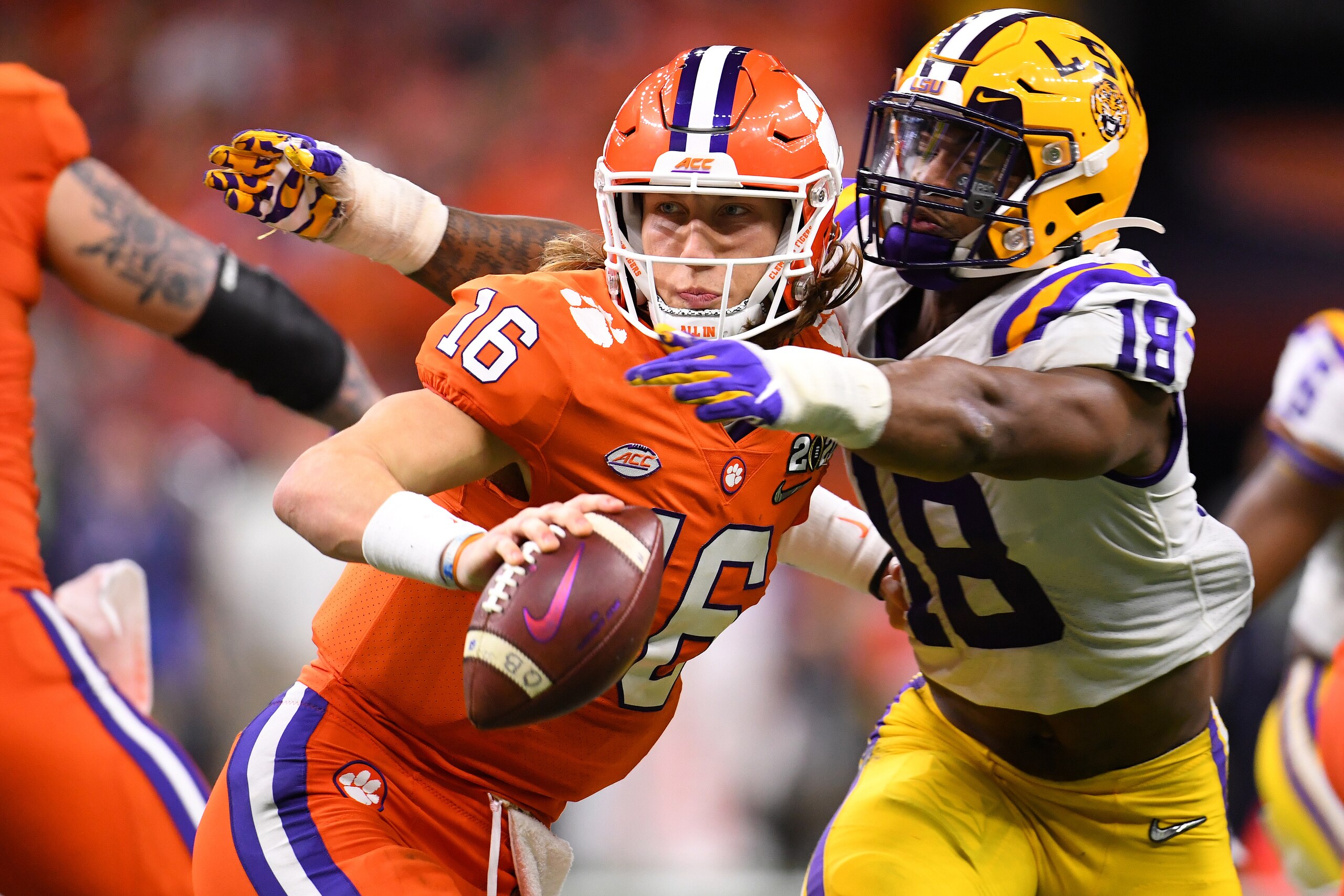 NEW ORLEANS, LA - JANUARY 13: Trevor Lawrence #16 of the Clemson Tigers pitches the ball under duress by K'Lavon Chaisson #18 of the LSU Tigers during the College Football Playoff National Championship held at the Mercedes-Benz Superdome on January 13, 20