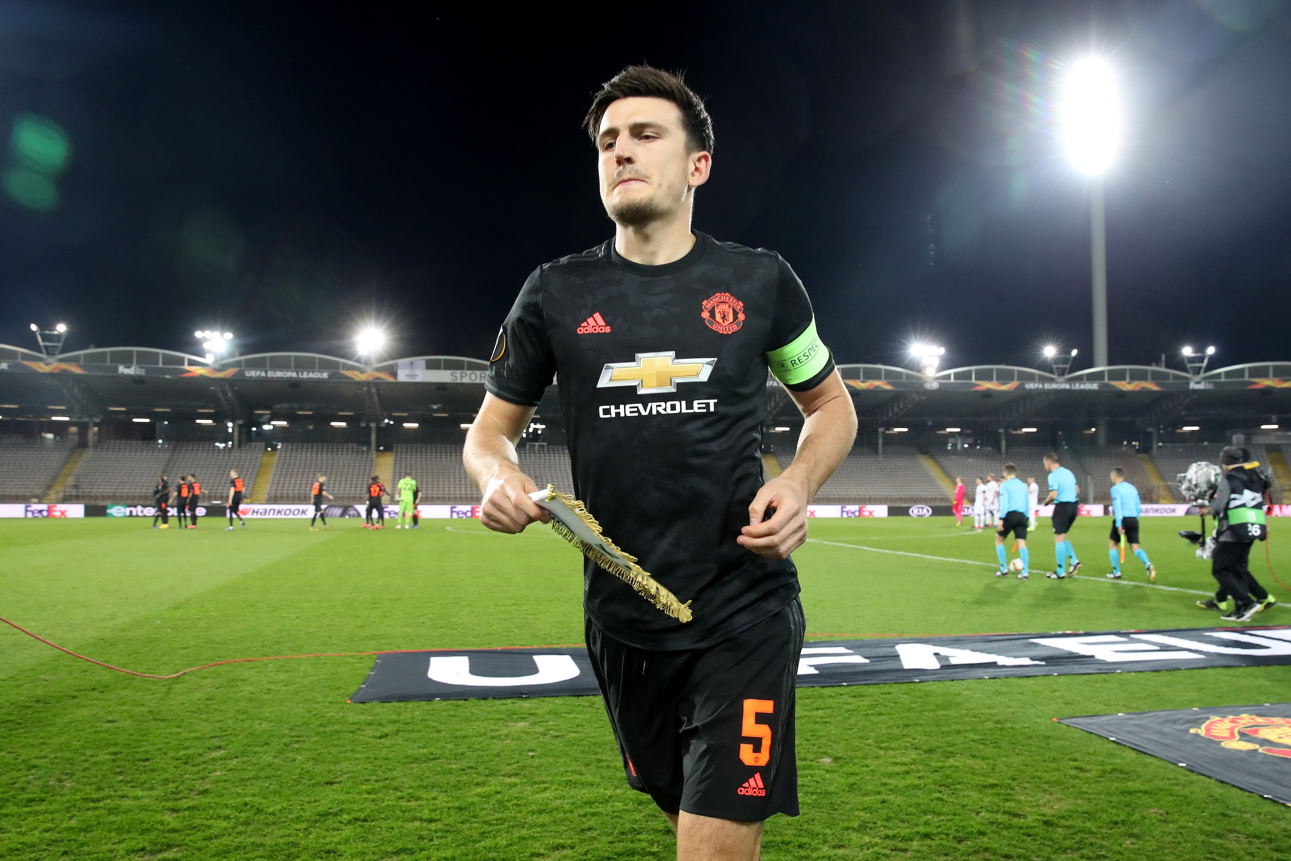 LINZ, AUSTRIA - MARCH 12: (FREE FOR EDITORIAL USE) In this handout image provided by UEFA, Harry Maguire of Manchester United collects the LASK team pennant prior to the UEFA Europa League round of 16 first leg match between LASK and Manchester United at 