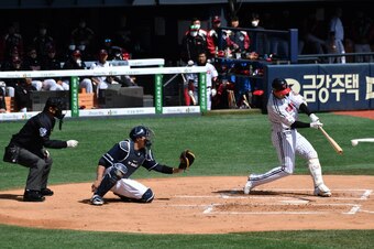 LG Twins' Chae Eun-seong (R) hits a ball during a pre-season baseball game between Seoul-based Doosan Bears and LG Twins at Jamsil stadium in Seoul on April 21, 2020. - Professional sport returned to South Korea on April 21 as coronavirus restrictions eas