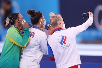 TOKYO, JAPAN - JULY 29: (L-R) Silver medalist Rebeca Andrade of Team Brazil, gold medalist Sunisa Lee of Team United States and bronze medalist Angelina Melnikova of Team ROC take a selfie after the Women's All-Around Final on day six of the Tokyo 2020 Ol