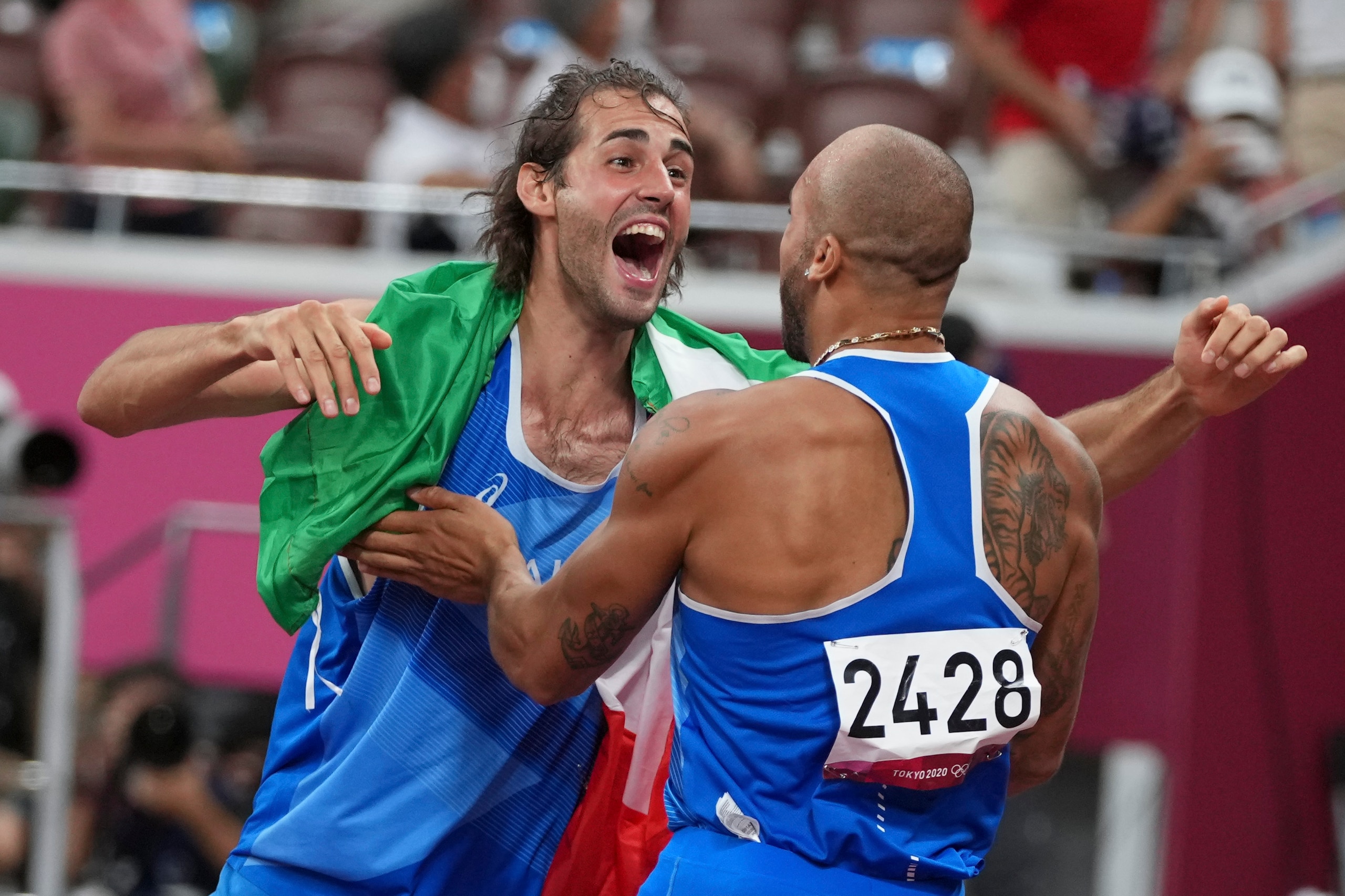 Italian Gianmarco Tamberi, who had just won gold in the high jump, celebrates with Jacobs after Jacobs' 100 win.