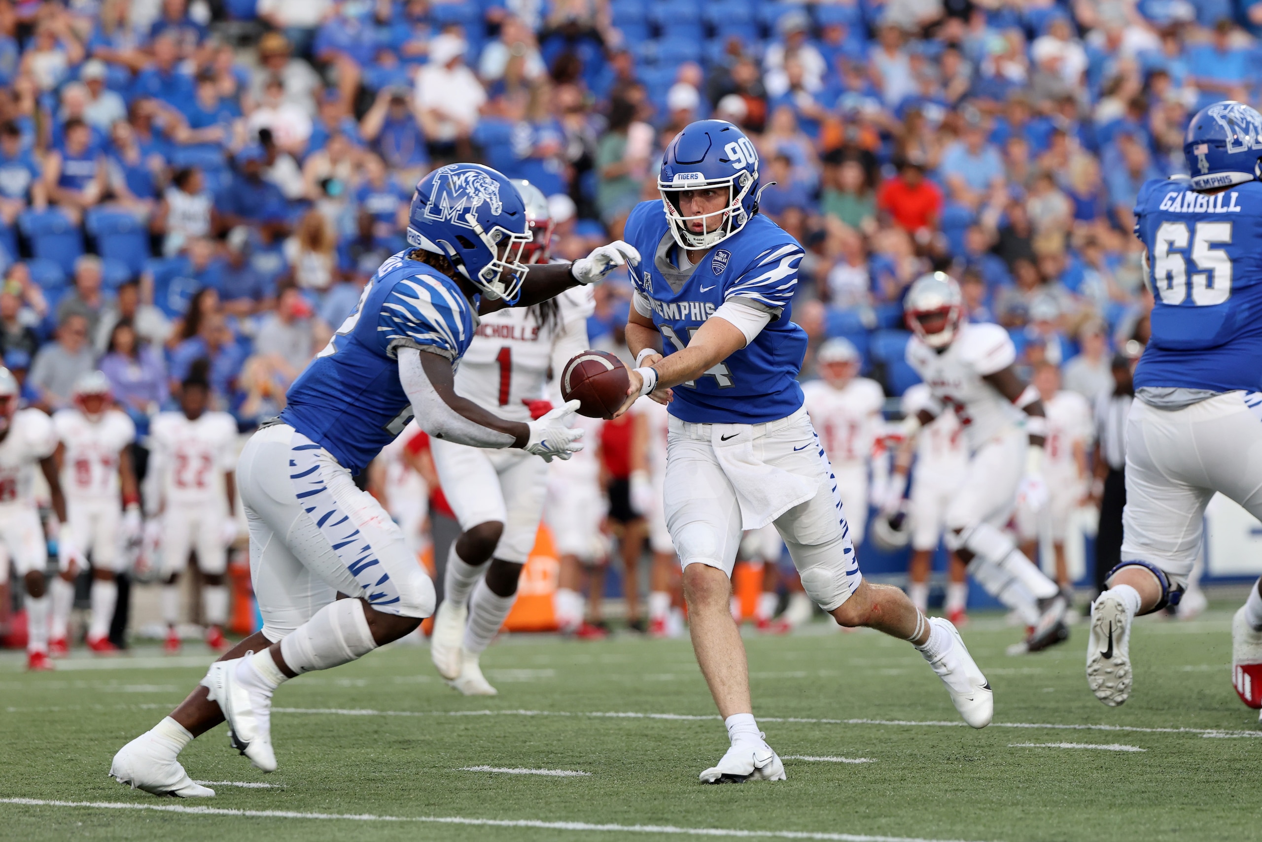MEMPHIS, TN - SEPTEMBER 4: Seth Henigan #14 of the Memphis Tigers hands the ball off to Brandon Thomas #22 of the Memphis Tigers against the Nicholls Colonels on September 4, 2021 at Liberty Bowl Memorial Stadium in Memphis, Tennessee. The Memphis Tigers MEMPHIS, TN - SEPTEMBER 4: Seth Henigan #14 of the Memphis Tigers hands the ball off to Brandon Thomas #22 of the Memphis Tigers against the Nicholls Colonels on September 4, 2021 at Liberty Bowl Memorial Stadium in Memphis, Tennessee. The Memphis Tigers