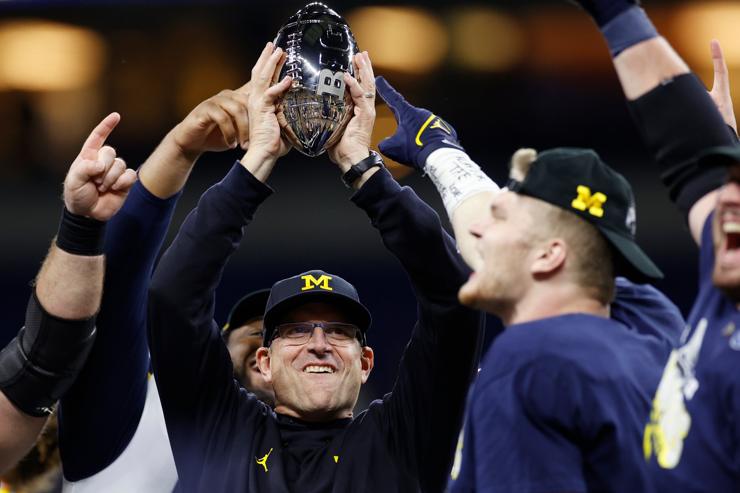 INDIANAPOLIS, IN - DECEMBER 04: Michigan Wolverines head coach Jim Harbaugh holds the champion trophy high after a win in the Big Ten Championship college football game against the Iowa Hawkeyes on Dec. 4, 2021 at Lucas Oil Stadium in Indianapolis, Indian INDIANAPOLIS, IN - DECEMBER 04: Michigan Wolverines head coach Jim Harbaugh holds the champion trophy high after a win in the Big Ten Championship college football game against the Iowa Hawkeyes on Dec. 4, 2021 at Lucas Oil Stadium in Indianapolis, Indian