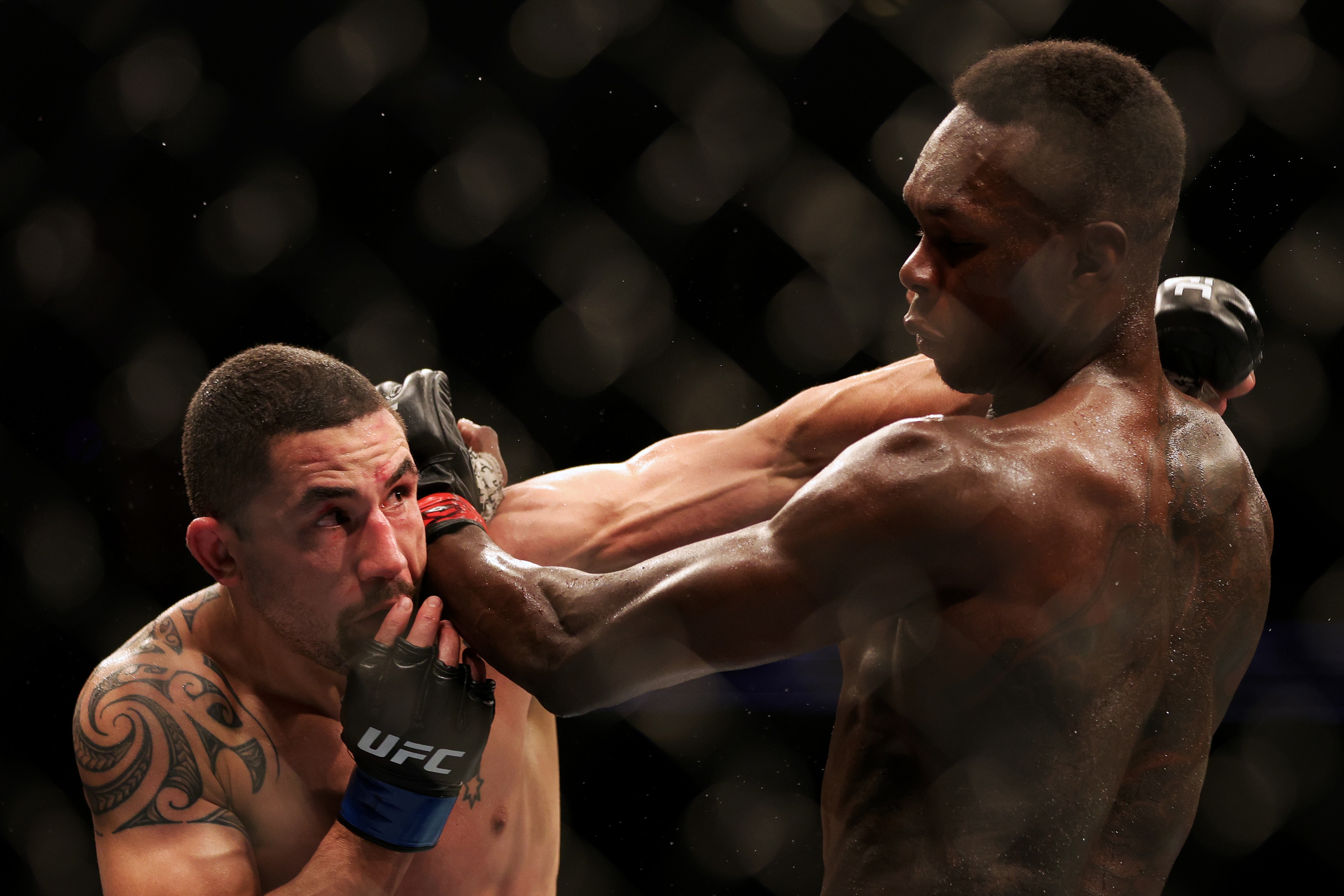 HOUSTON, TEXAS - FEBRUARY 12: Robert Whittaker (L) of Australia exchanges strikes with Israel Adesanya of Nigeria in their middleweight championship fight during UFC 271 at Toyota Center on February 12, 2022 in Houston, Texas. (Photo by Carmen Mandato/Get