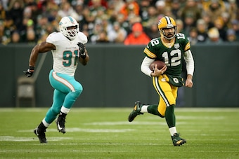GREEN BAY, WISCONSIN - NOVEMBER 11:  Aaron Rodgers #12 of the Green Bay Packers runs with the ball while being chased by Cameron Wake #91 of the Miami Dolphins in the first quarter at Lambeau Field on November 11, 2018 in Green Bay, Wisconsin. (Photo by D