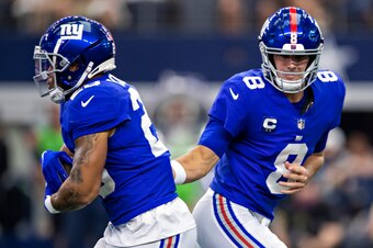 ARLINGTON, TEXAS - OCTOBER 10:  Daniel Jones #8 hands off the ball to Saquon Barkley #26 of the New York Giants during a game against the Dallas Cowboys at AT&T Stadium on October 10, 2021 in Arlington, Texas.  The Cowboys defeated the Giants 44-20.  (Pho