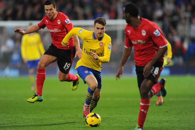 CARDIFF, WALES - NOVEMBER 30:  Aaron Ramsey of Arsenal runs between Don Cowie (L) and Kevin Theophile-Catherine of Cardiff during the Barclays Premier League match between Cardiff City and Arsenal at Cardiff City Stadium on November 30, 2013 in Cardiff, Wales.  (Photo by Mike Hewitt/Getty Images)