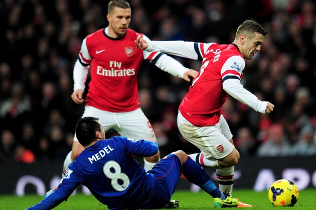LONDON, ENGLAND - JANUARY 01:  Jack Wilshere of Arsenal (R) evades Gary Medel of Cardiff City as Lukas Podolski of Arsenal looks on during the Barclays Premier League match between Arsenal and Cardiff City at Emirates Stadium on January 1, 2014 in London, England.  (Photo by Shaun Botterill/Getty Images)
