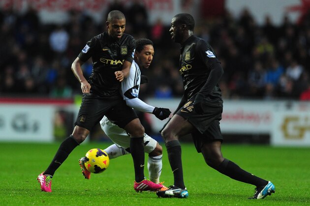 SWANSEA, WALES - JANUARY 01:  Manchester City players Fernandinho (l) and Yaya Toure (r) combine to halt Jonathan de Guzman during the Barclays Premier League match between Swansea City and Manchester City at Liberty Stadium on January 1, 2014 in Swansea, Wales.  (Photo by Stu Forster/Getty Images)