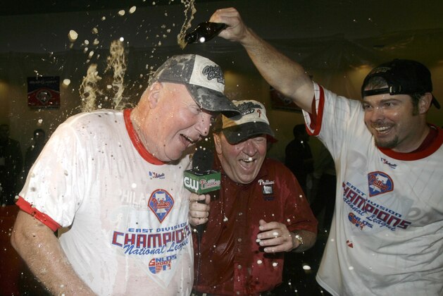 PHILADELPHIA - SEPTEMBER 30:   Charlie Manuel, manager of the Philadelphia Phillies (L)  is sprayed with beer by pitcher Adam Eaton (R) as he is being interview by television reporter Chris Wheeler, center, in the Phillies clubhouse at Citizens Bank Park September 30, 2007 in Philadelphia Pennsylvania.  (Photo by Chris Gardner/Getty Images)
