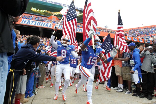 November 17, 2012; Gainesville FL, USA; Florida Gators defensive back Loucheiz Purifoy (15), defensive back Jeremy Brown (8) and teammates run out of the tunnel holding flags in honor of military prior to the game against the Jacksonville State Gamecocks at Ben Hill Griffin Stadium. Mandatory Credit: Kim Klement-USA TODAY Sports