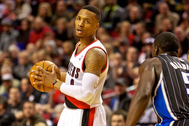Jan 8, 2014; Portland, OR, USA; Portland Trail Blazers point guard Damian Lillard (0) looks to pass around Orlando Magic shooting guard Victor Oladipo (5) at the Moda Center. Mandatory Credit: Craig Mitchelldyer-USA TODAY Sports